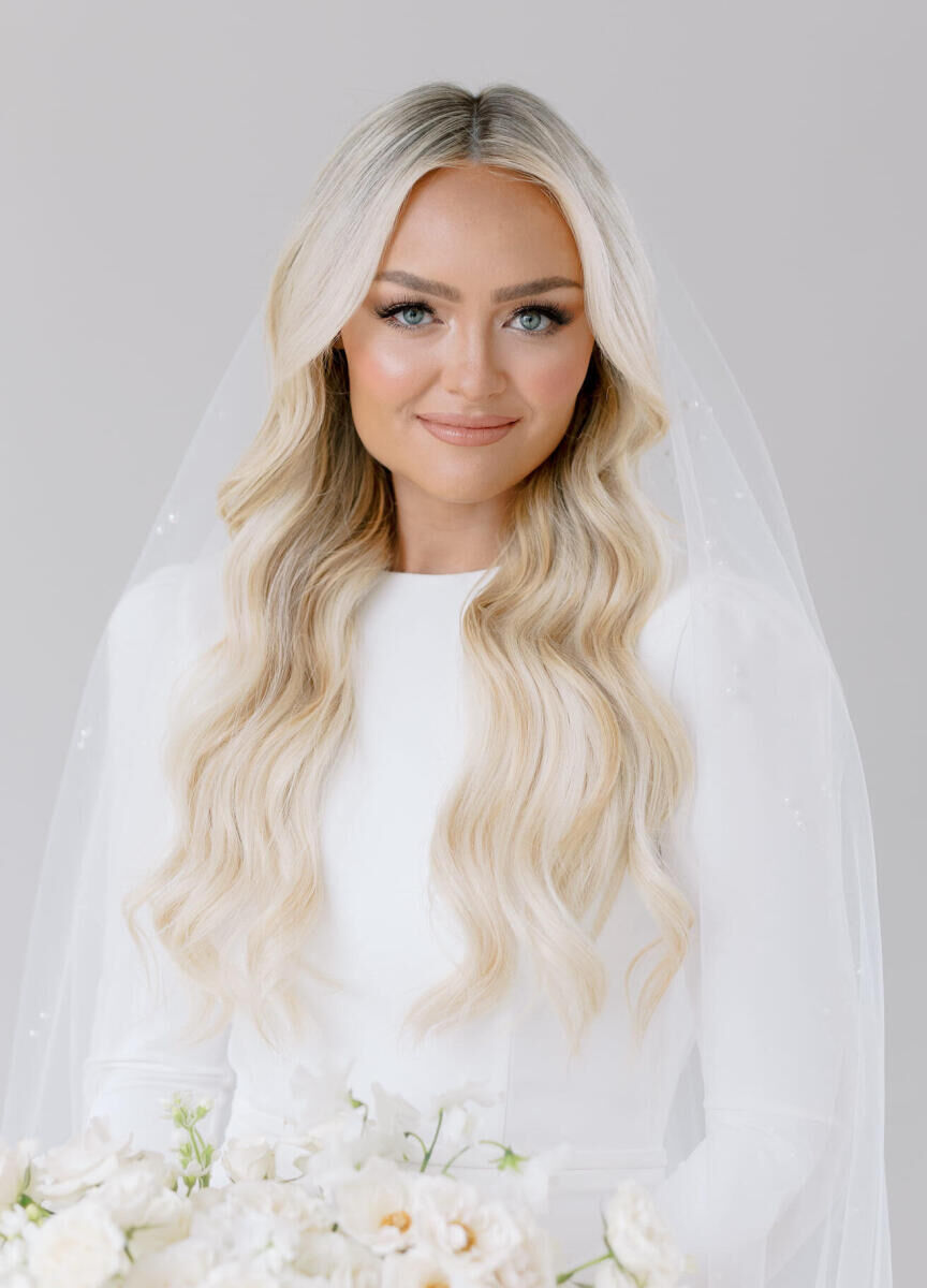 A bride wears a glam-yet-natural look with long waves and understated makeup on the day of her modern California wedding.