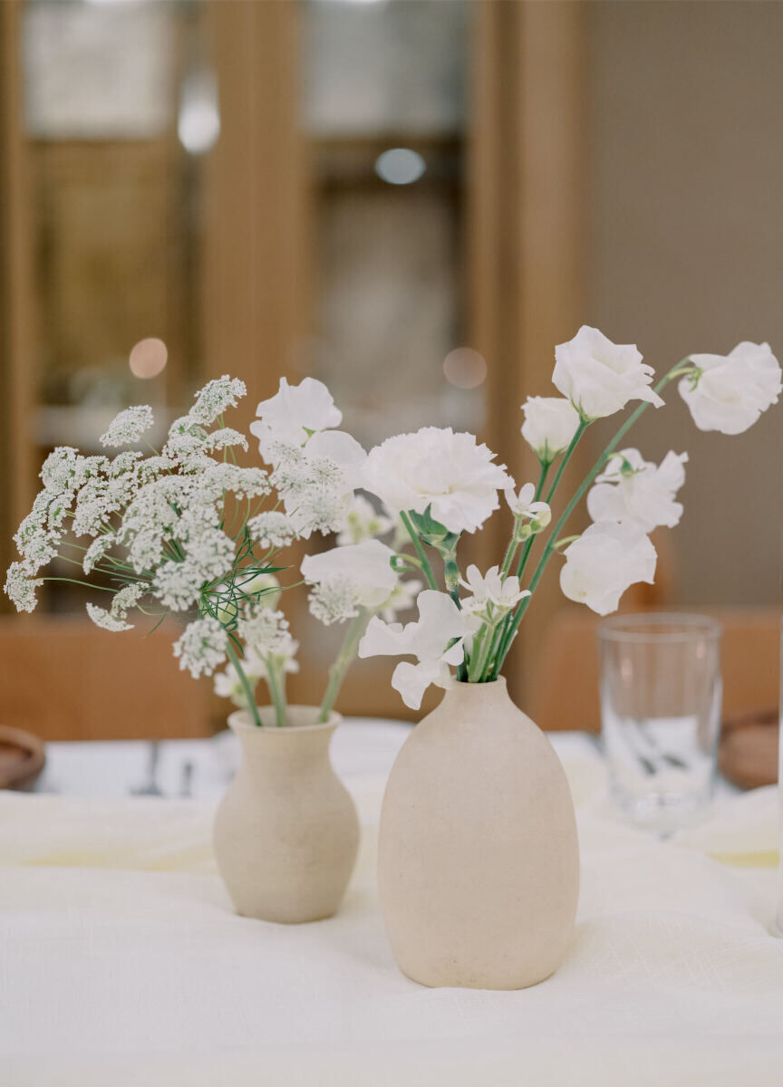 Organic vases held all-white floral arrangements at a modern California wedding reception in Santa Monica.