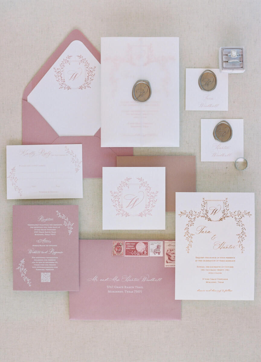 A pink-and-white modern fairytale wedding invitation, with a garland motif, monogram, and wax seal.