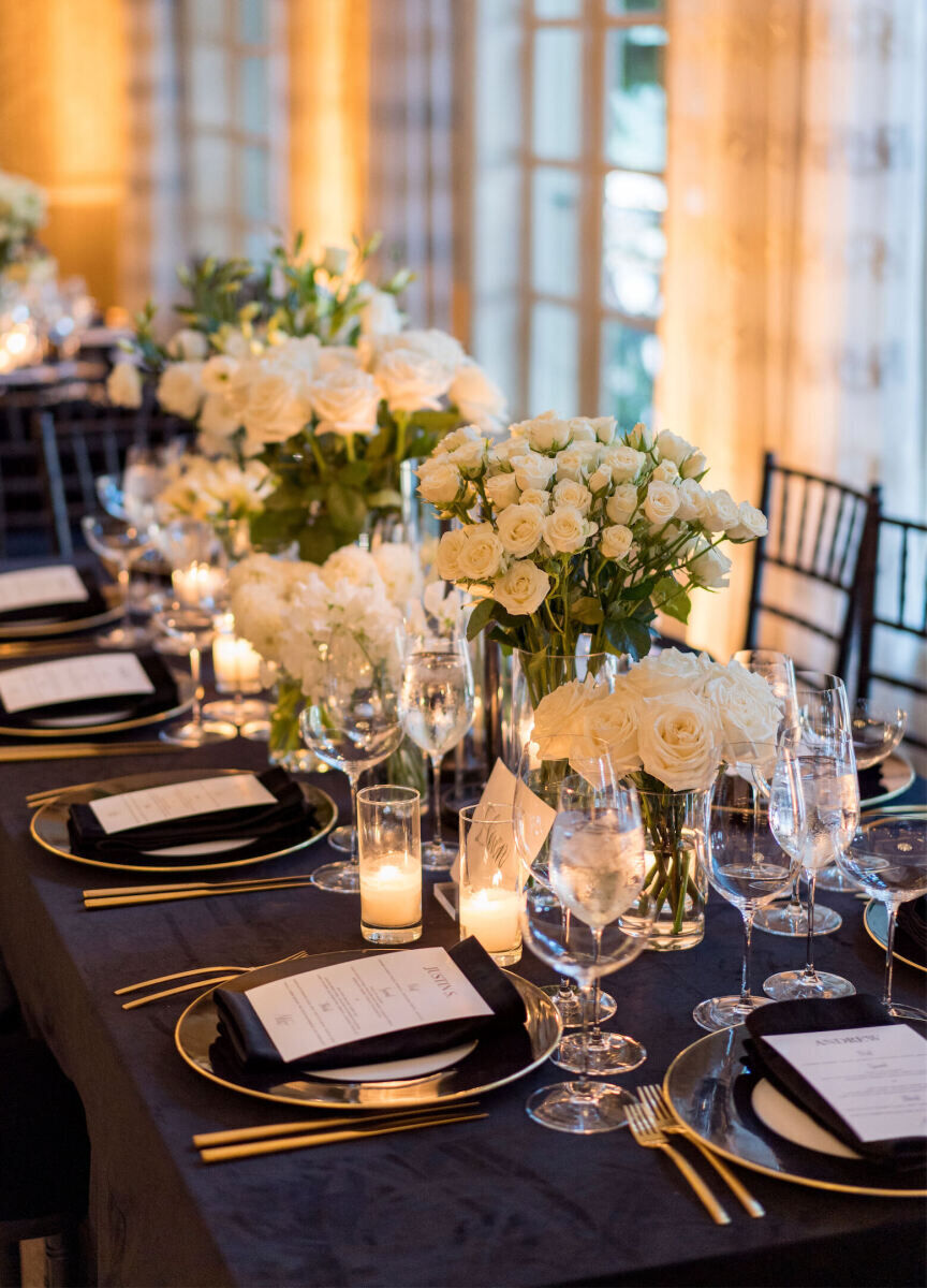 A modern wedding reception inside a ballroom of a Los Angeles hotel incorporated gold chargers and flatware, black velvet linens, and lots of white flowers in clear vases.