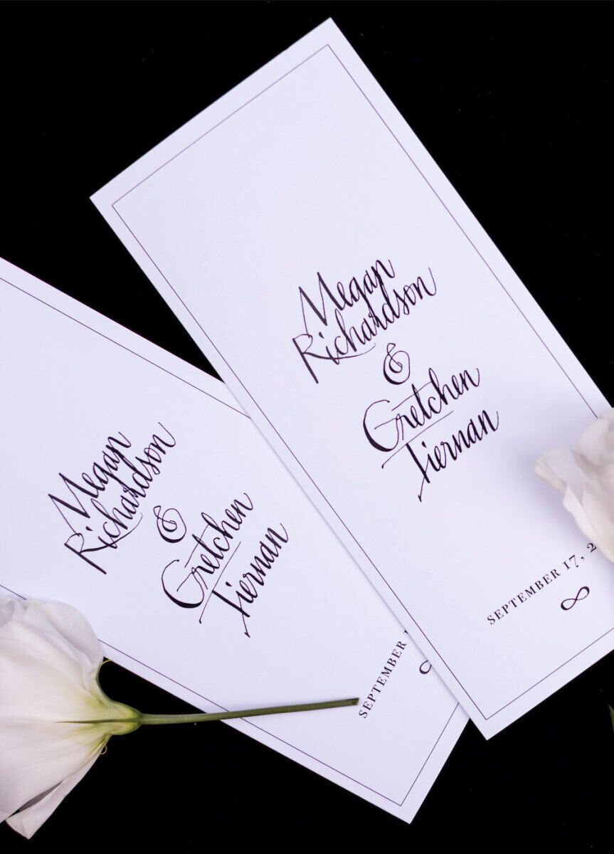 Black and white ceremony programs featuring modern wedding calligraphy and an infinity symbol.