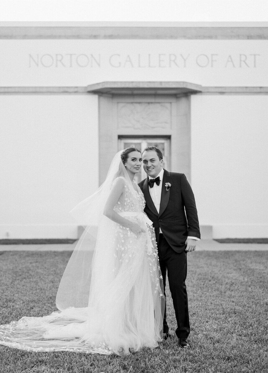 A bride and groom pause for a black-and-white photo outside of the Norton Museum of Art.