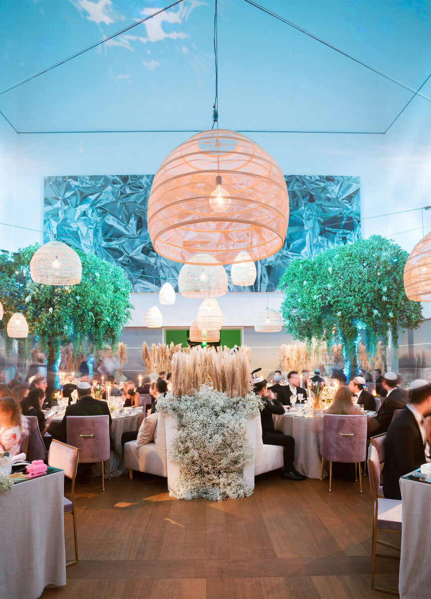 An interior space of the Norton Museum of Art was used for a wedding reception, decorated with large light fixtures and small trees.