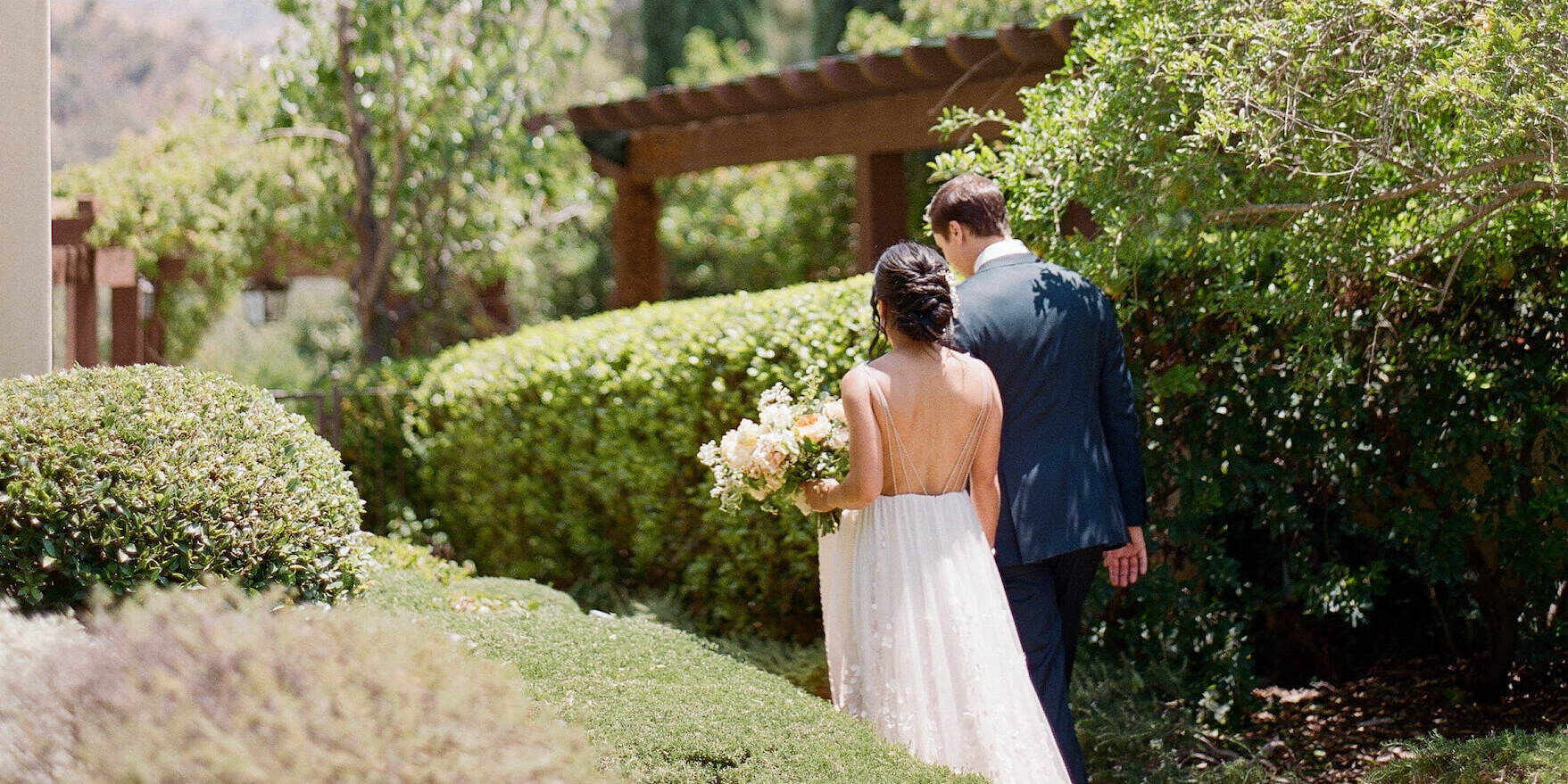 A bride and groom walk the grounds of Ojai Valley Inn on their wedding day.