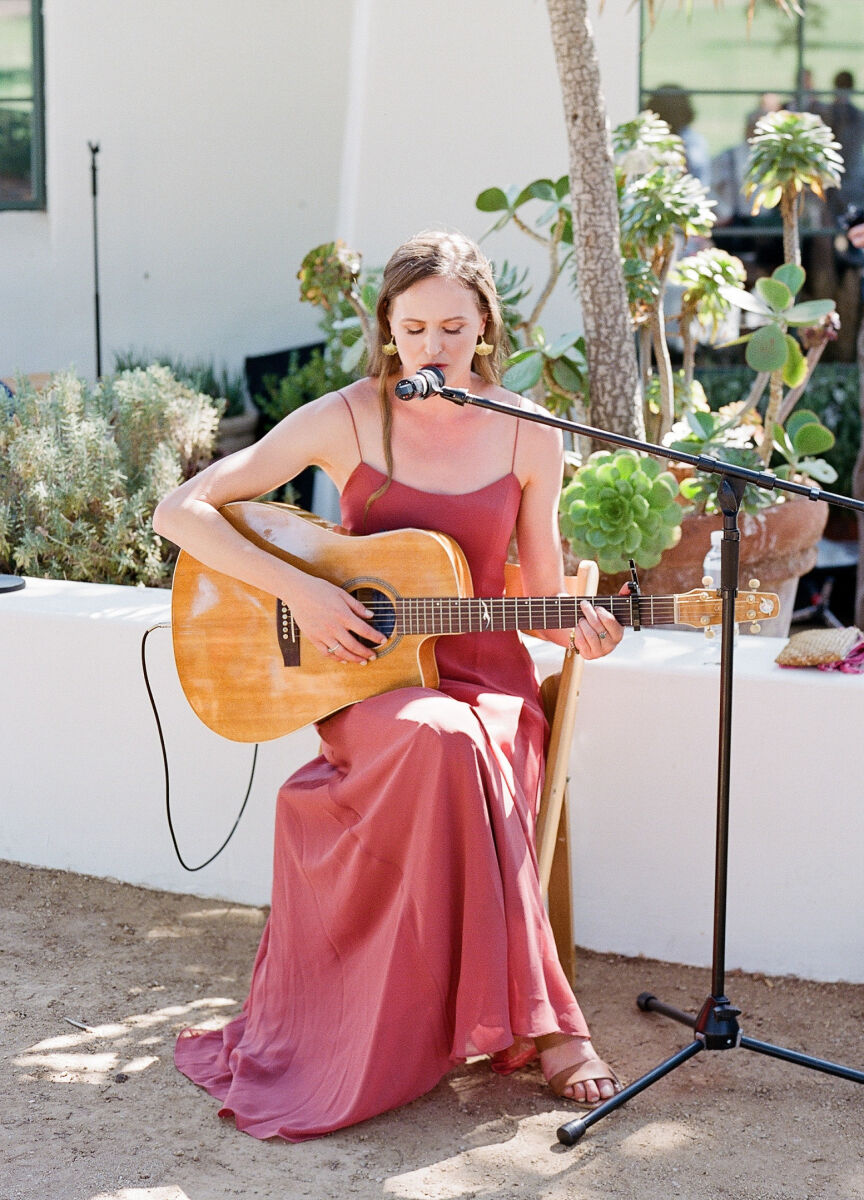 A bridesmaids plays guitar and sings during an outdoor wedding ceremony in Ojai.