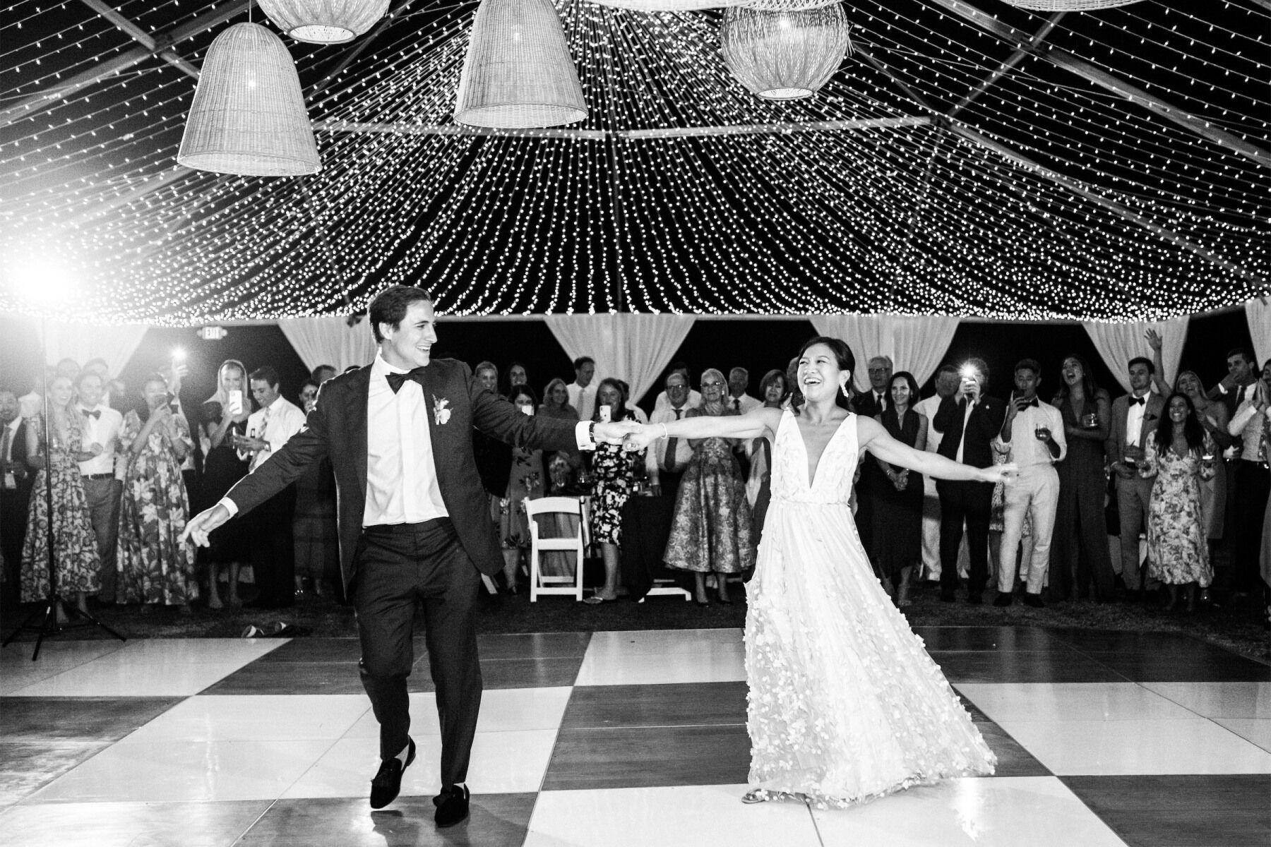 Newlyweds during their first dance on a checkerboard dance floor.