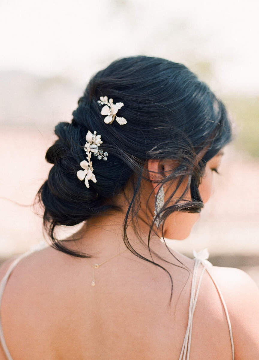 A loose, bridal updo decorated with floral hair jewelry.