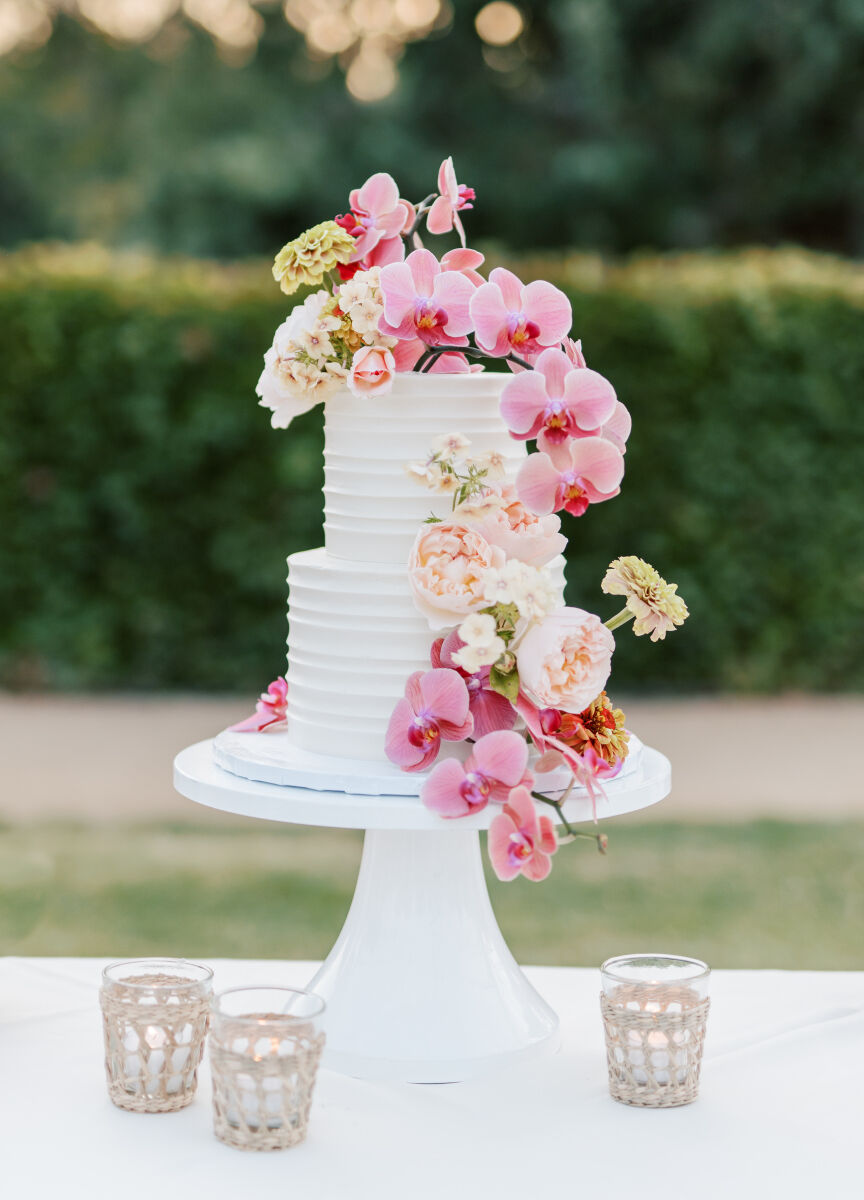 A petite two-tier wedding cake decorated with a cascade of fresh pink flowers.