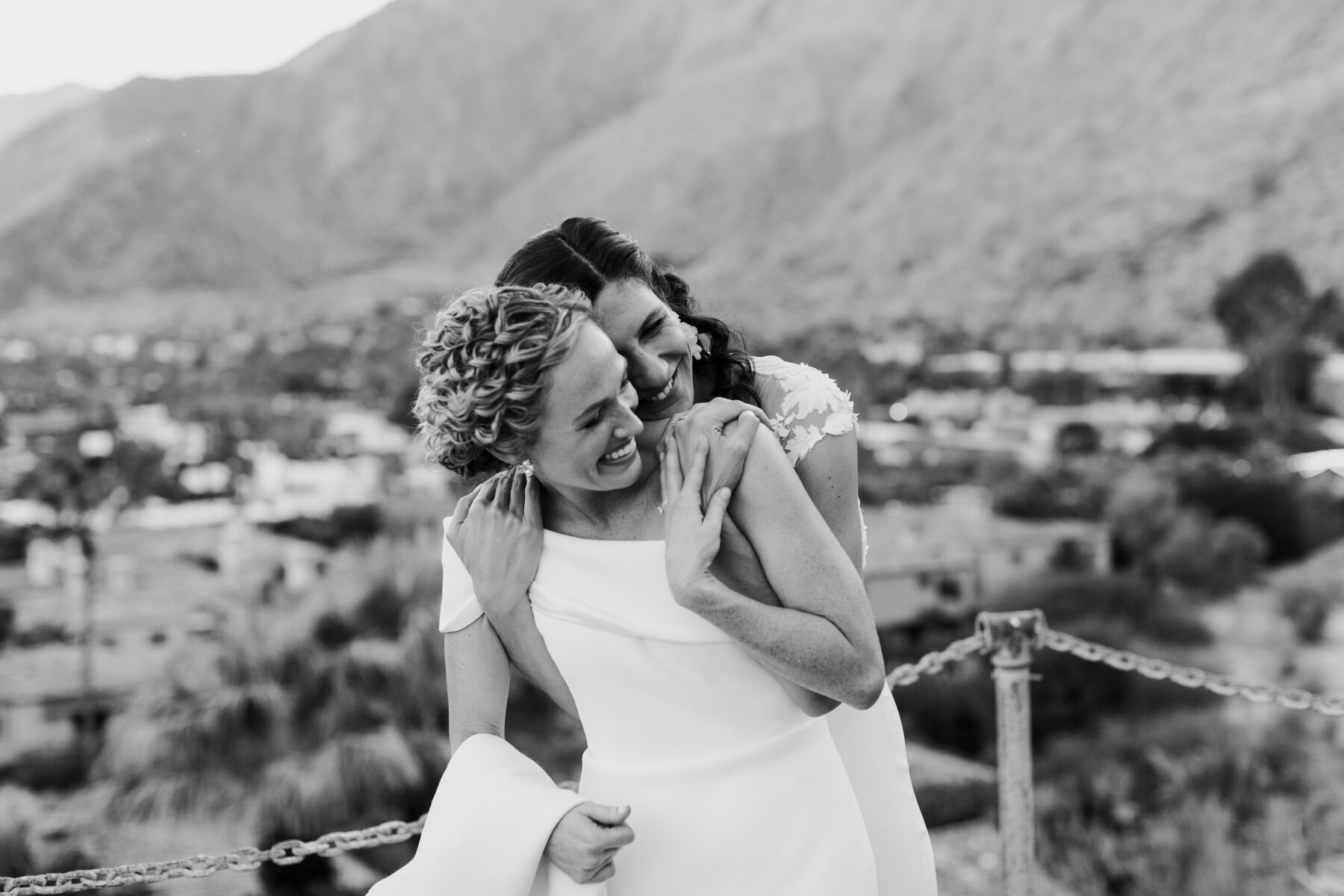 Pink Wedding: Two brides smiling and embracing on their wedding day in Palm Springs, California.
