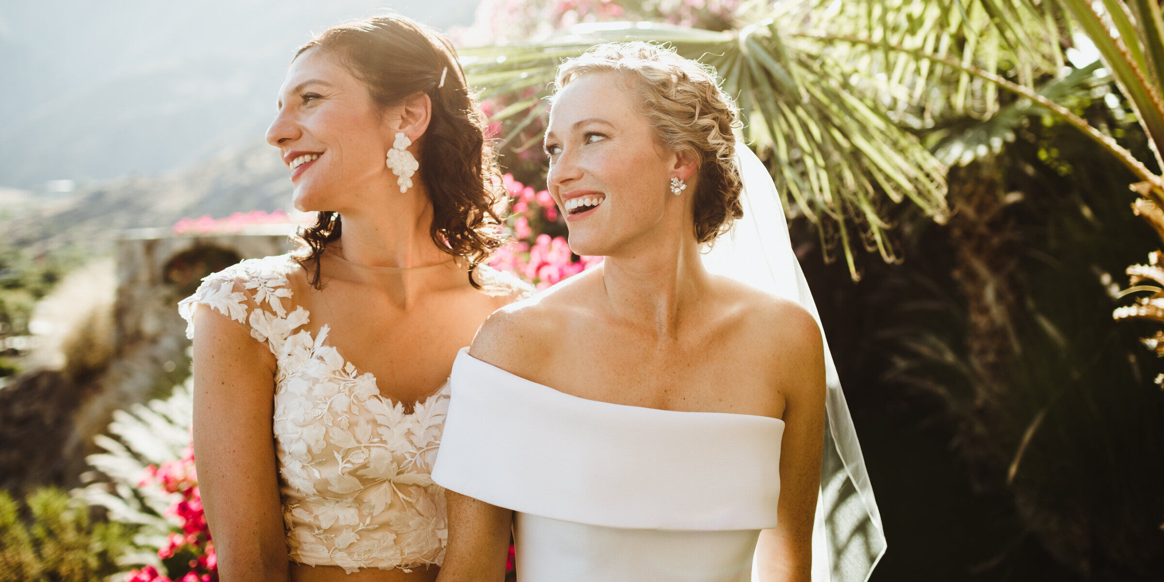 Pink Wedding: Two brides looking away and smiling on their wedding day.