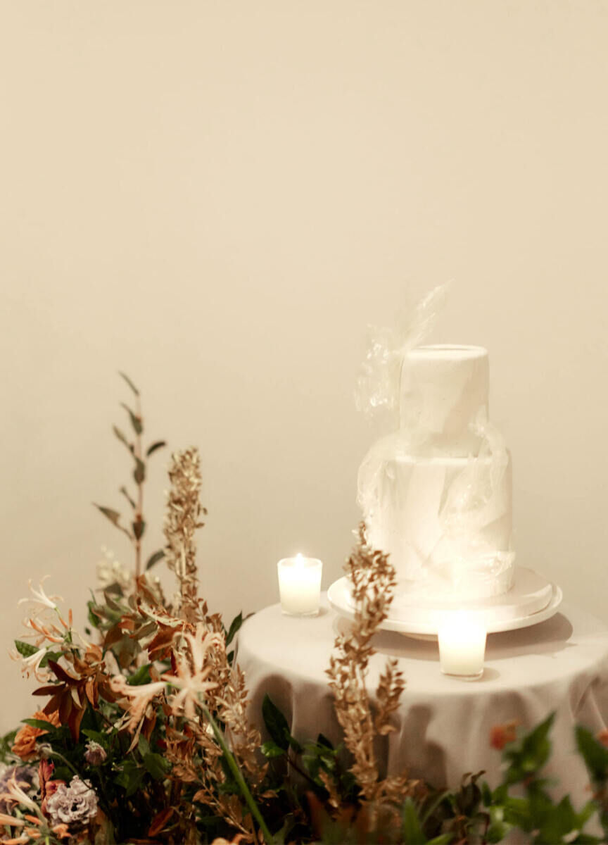 A petite wedding cake with translucent rice paper accents, on a table surrounded by autumnal flowers and foliage, at a restaurant wedding in New York City.