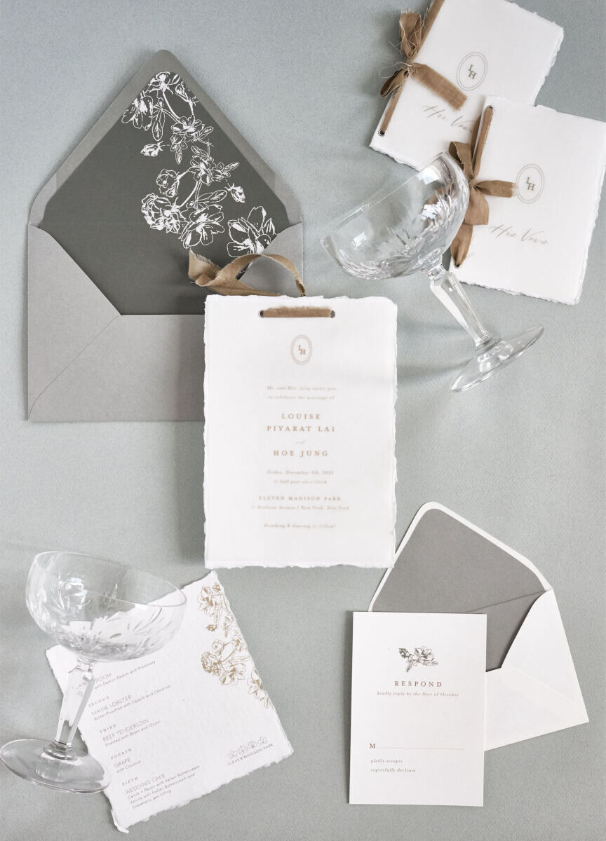 A neutral-toned wedding invitation, vow booklets, and menu for a restaurant wedding.