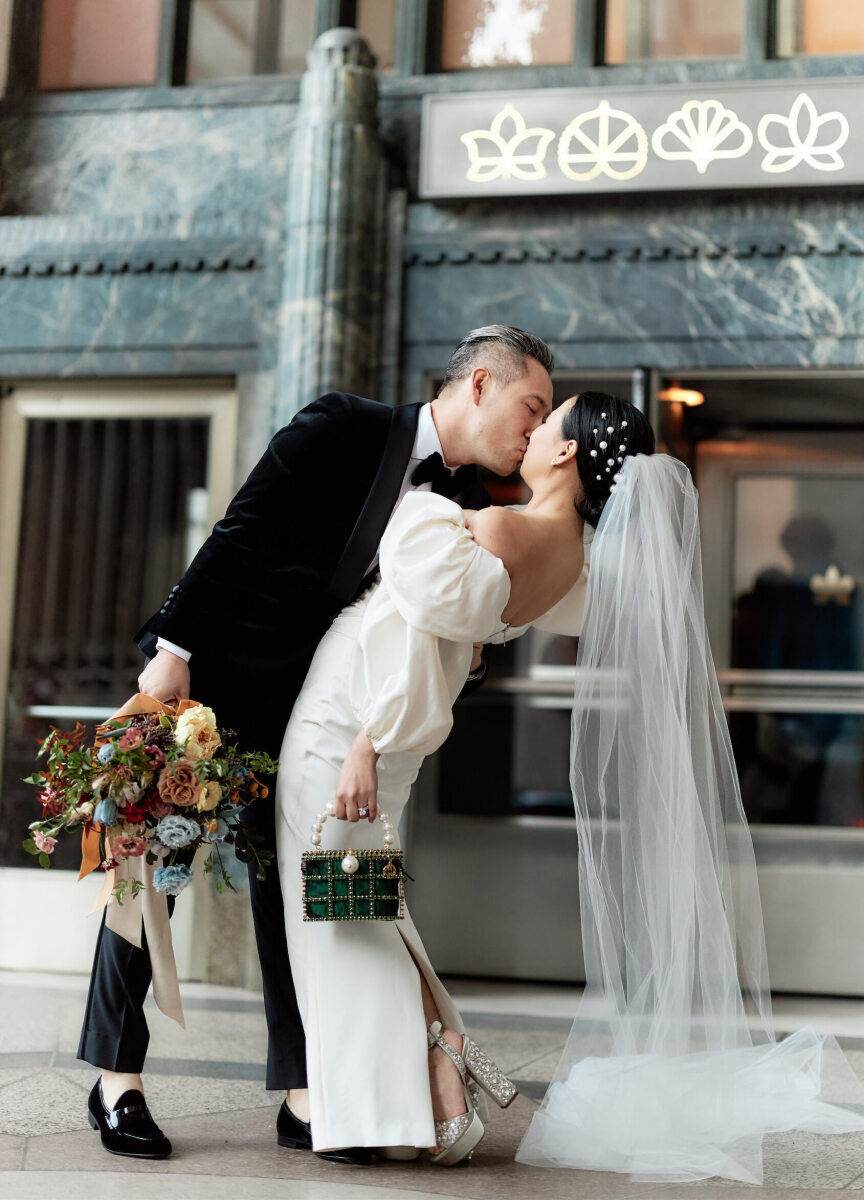 A groom and bride kiss outside the location of their restaurant wedding reception, Eleven Madison Park, in New York City.