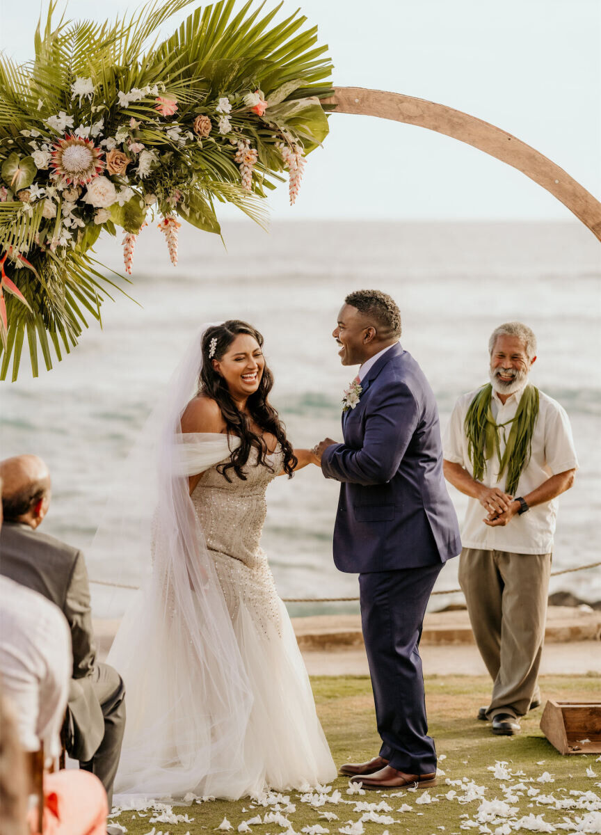 Restaurant Weddings: A couple holding hands during their ceremony in front of a circular archway near the ocean at The Beach House.