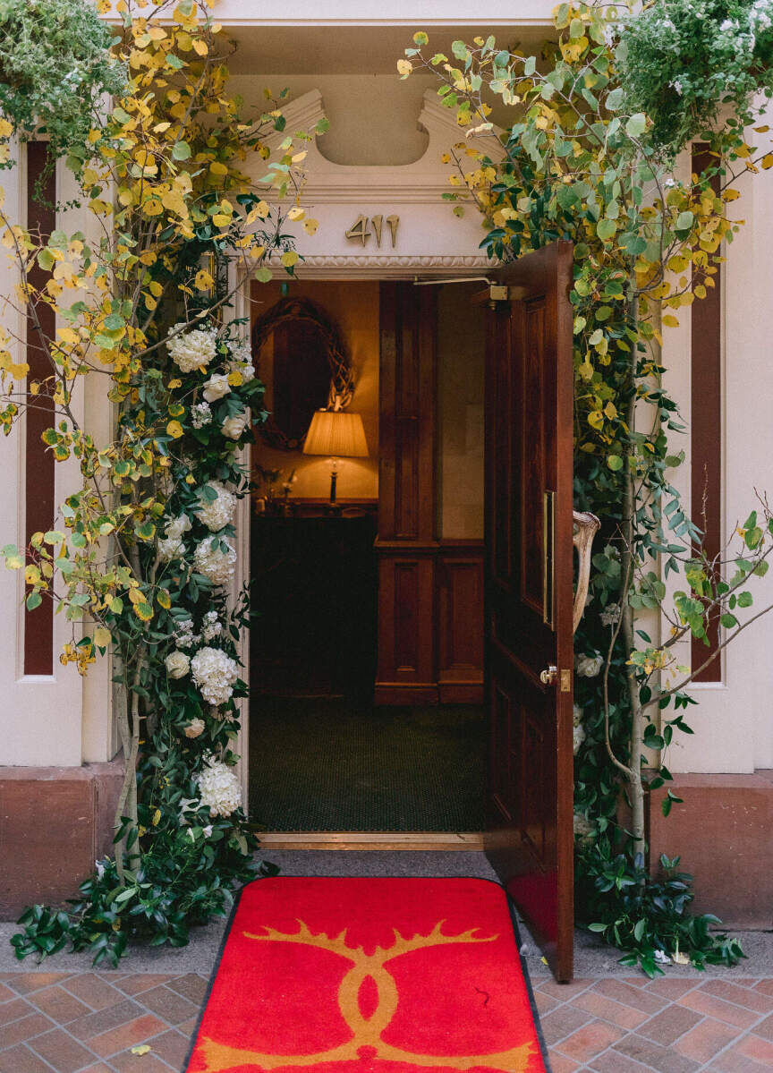 Restaurant Weddings: A greenery-lined entrance shot of the Caribou Club, with a red rug near the entranceway that has two Cs on it.