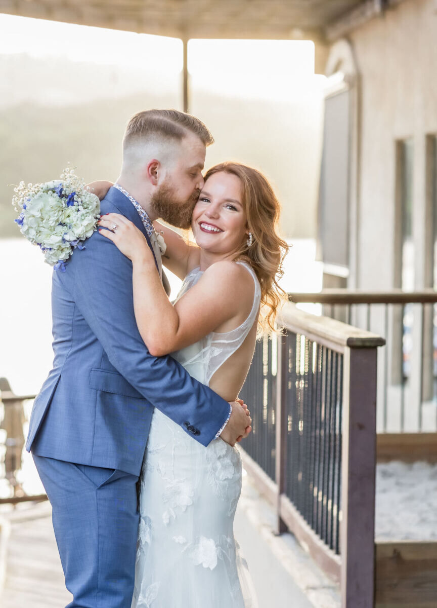 Restaurant Weddings: A groom kissing a smiling bride on the cheek as they stand on an outdoor dock.