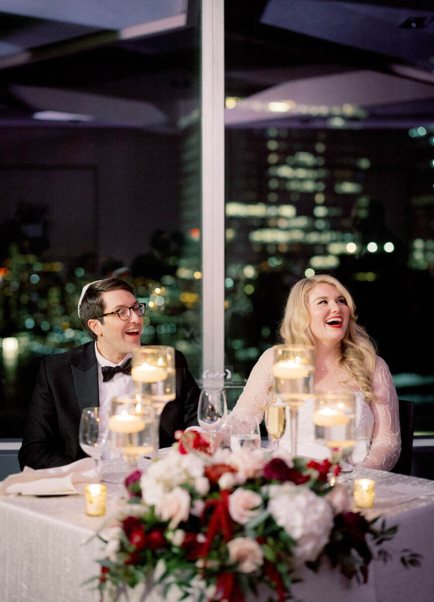Restaurant Weddings: A bride and groom sitting and smiling at a table with New York City in the background.