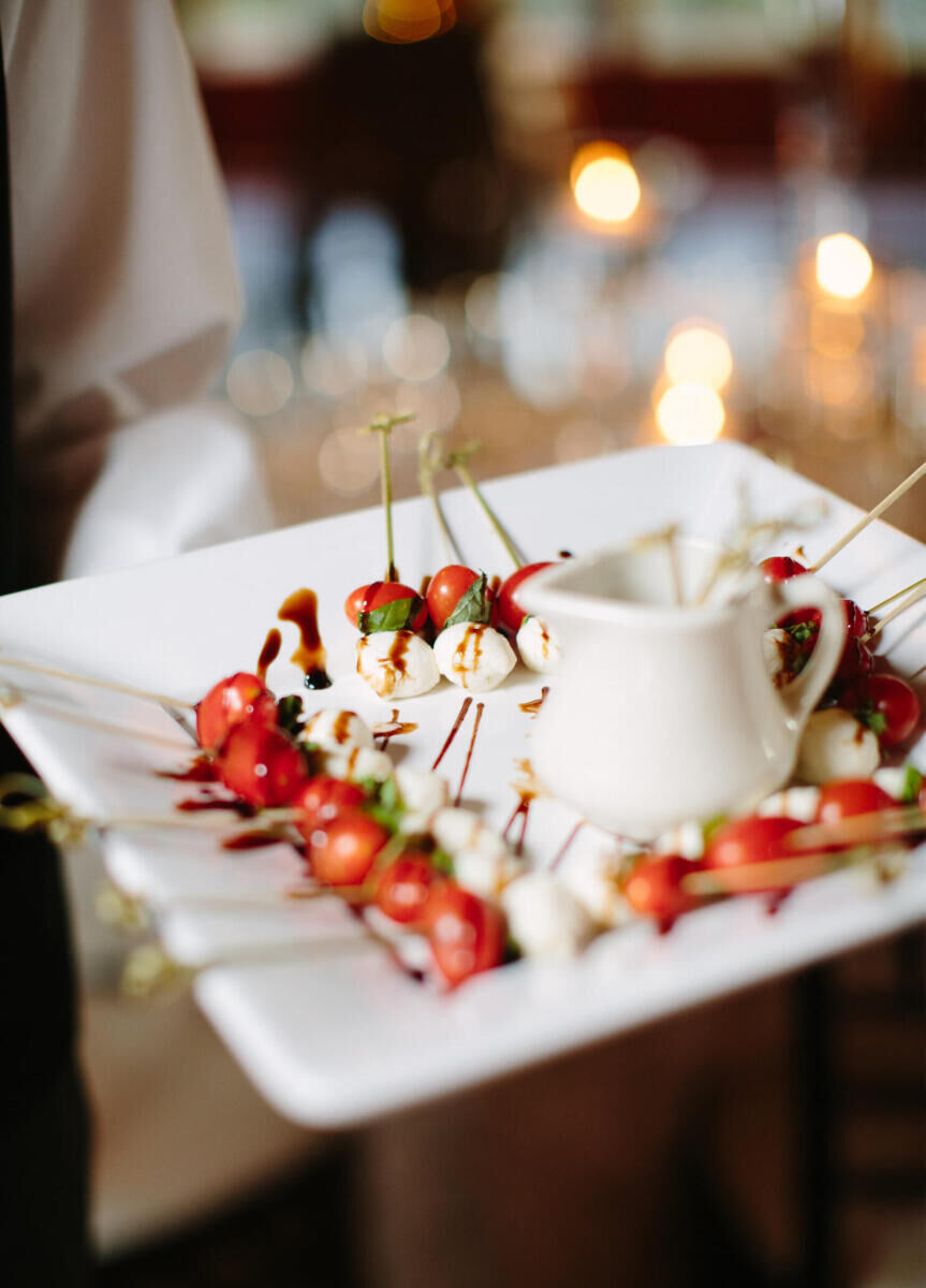 Restaurant Weddings: Tomato, mozzarella, and balsamic skewer hors d'oeuvres being passed on a white plate.
