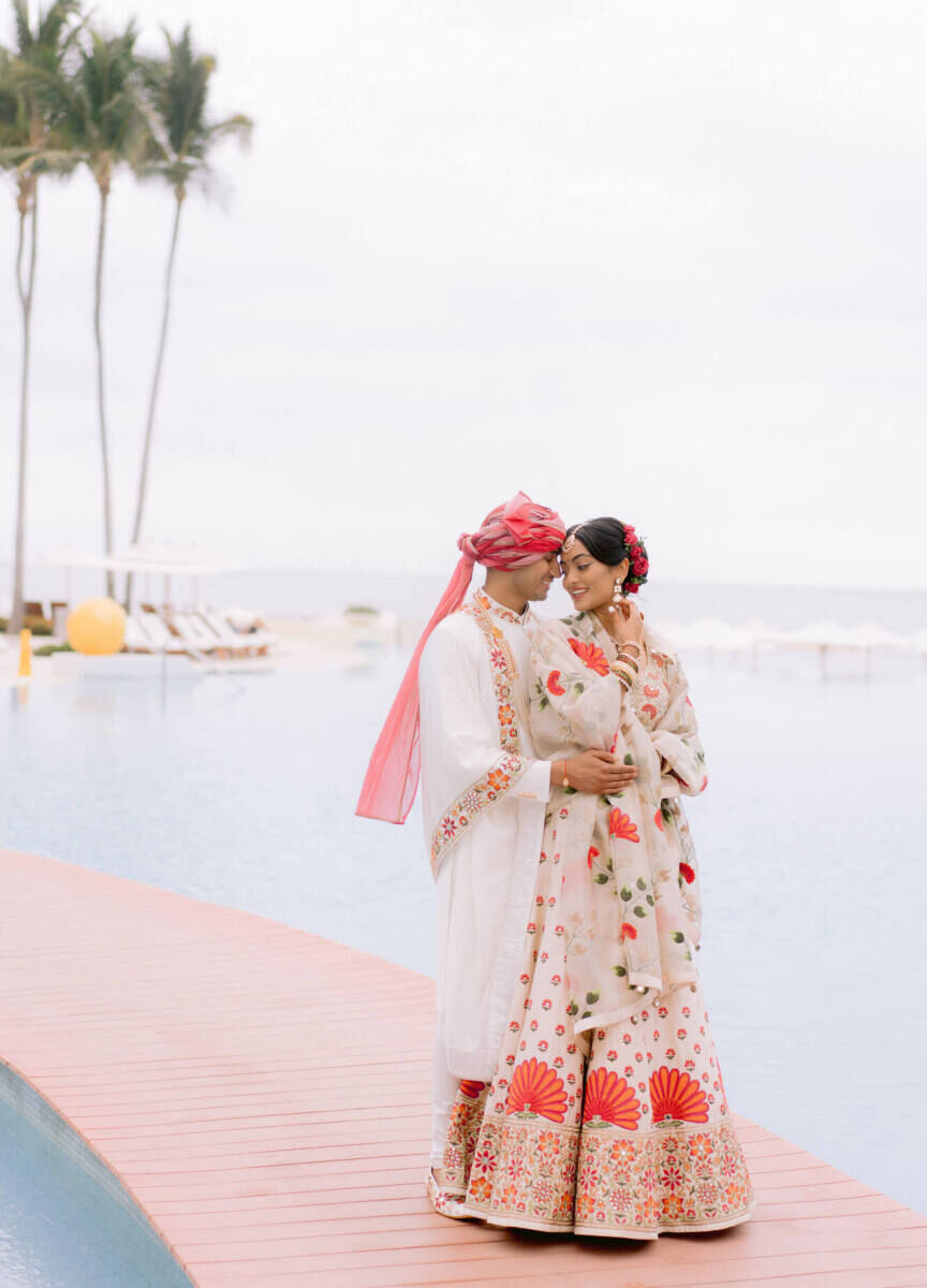 Romantic Wedding Venues: Newlyweds arm in arm on a walkway above the water at Grand Velas Riviera Nayarit.