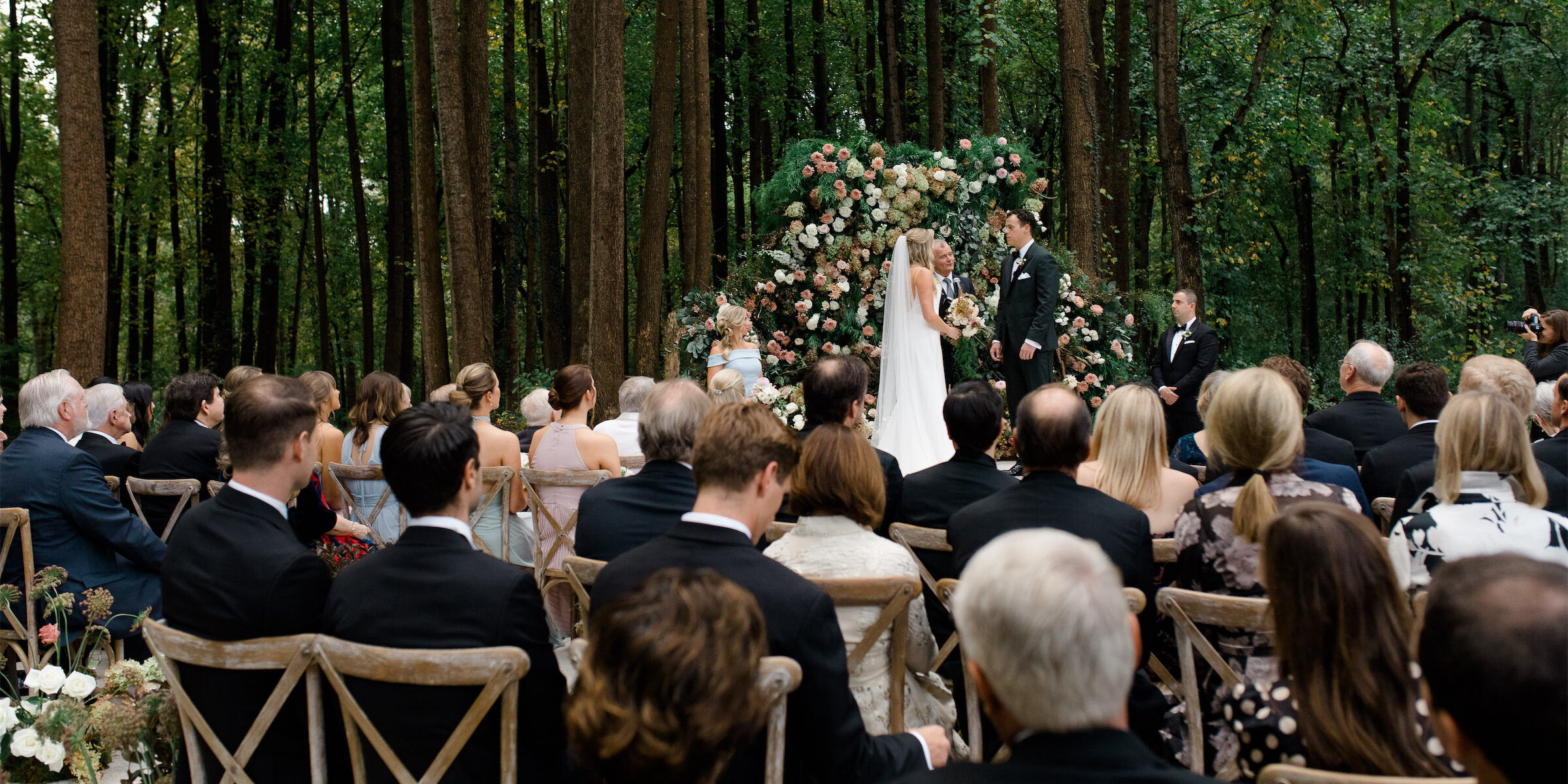 A pair of newlyweds standing at the flower-lined alter at their rustic outdoor wedding in Virginia.