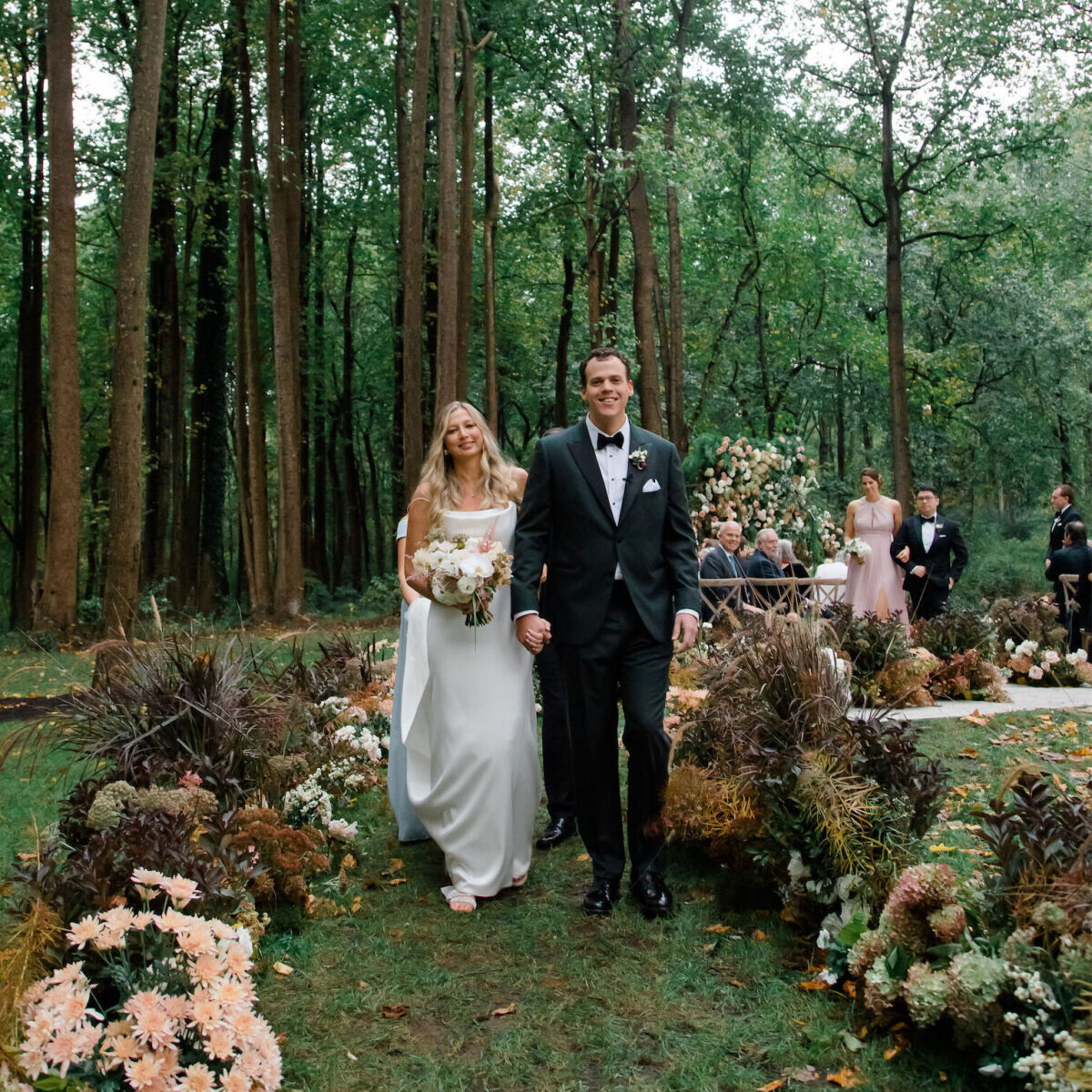 A pair of newlyweds recess up a flower-lined aisle at their rustic outdoor wedding in Virginia.