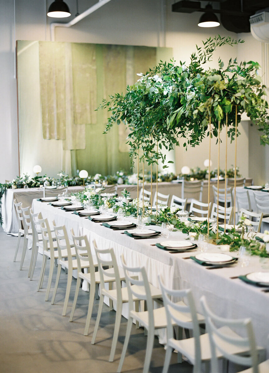 SEO for Wedding Venues: An indoor reception setup with an all white and green color palette and long tables.