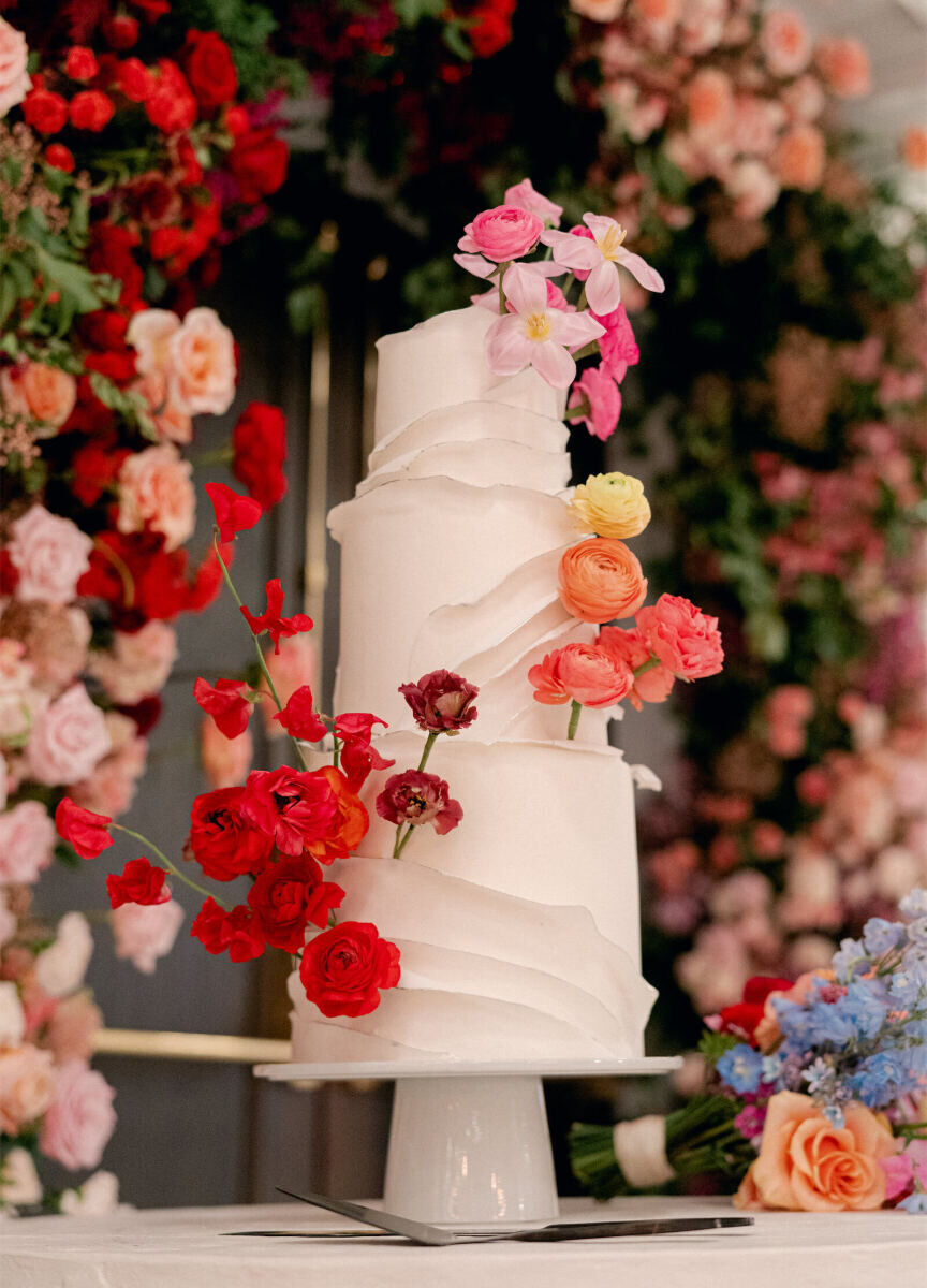 During the reception following their surprise wedding, a couple cut into a three-tier wedding cake decorated with a ruffle design and ombre of colors.