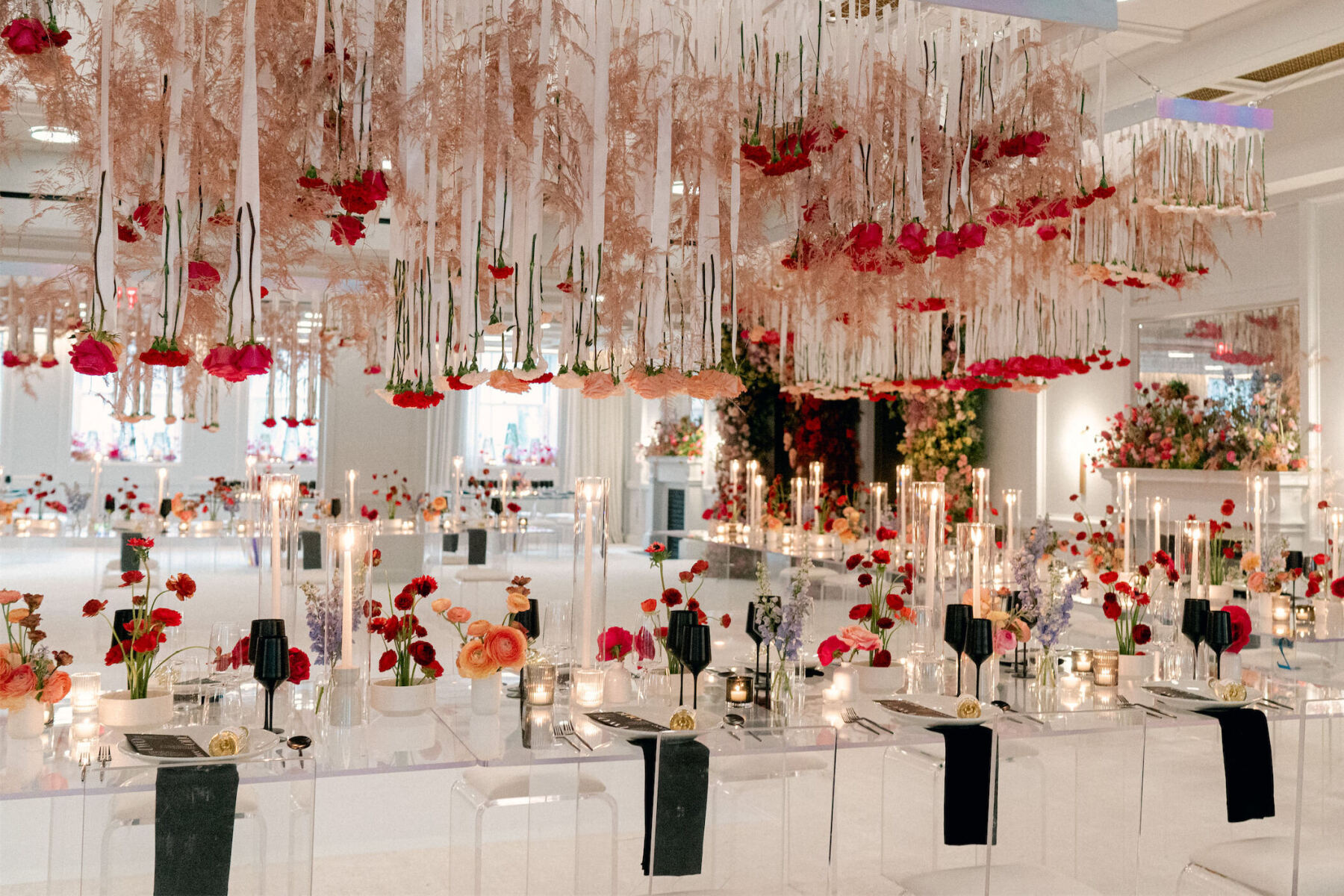 The ballroom of The Line Hotel in DC decorated in shades of black, white, pink, and red, using modern rental furniture, a hanging floral installation, and Ikebana style table centerpieces.