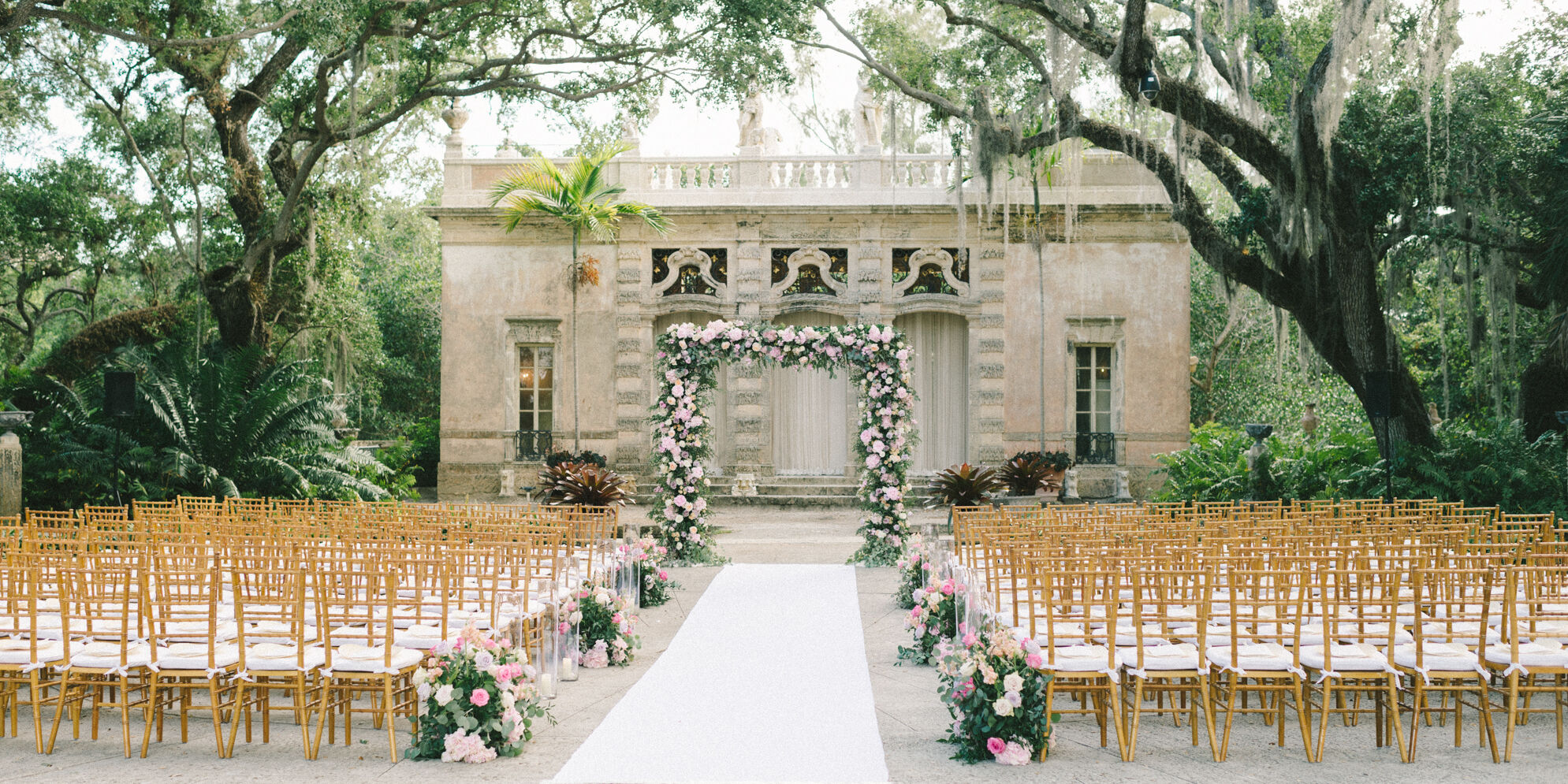 Pink flowers and greenery adorned the ceremony space at a glam, garden wedding in Miami.