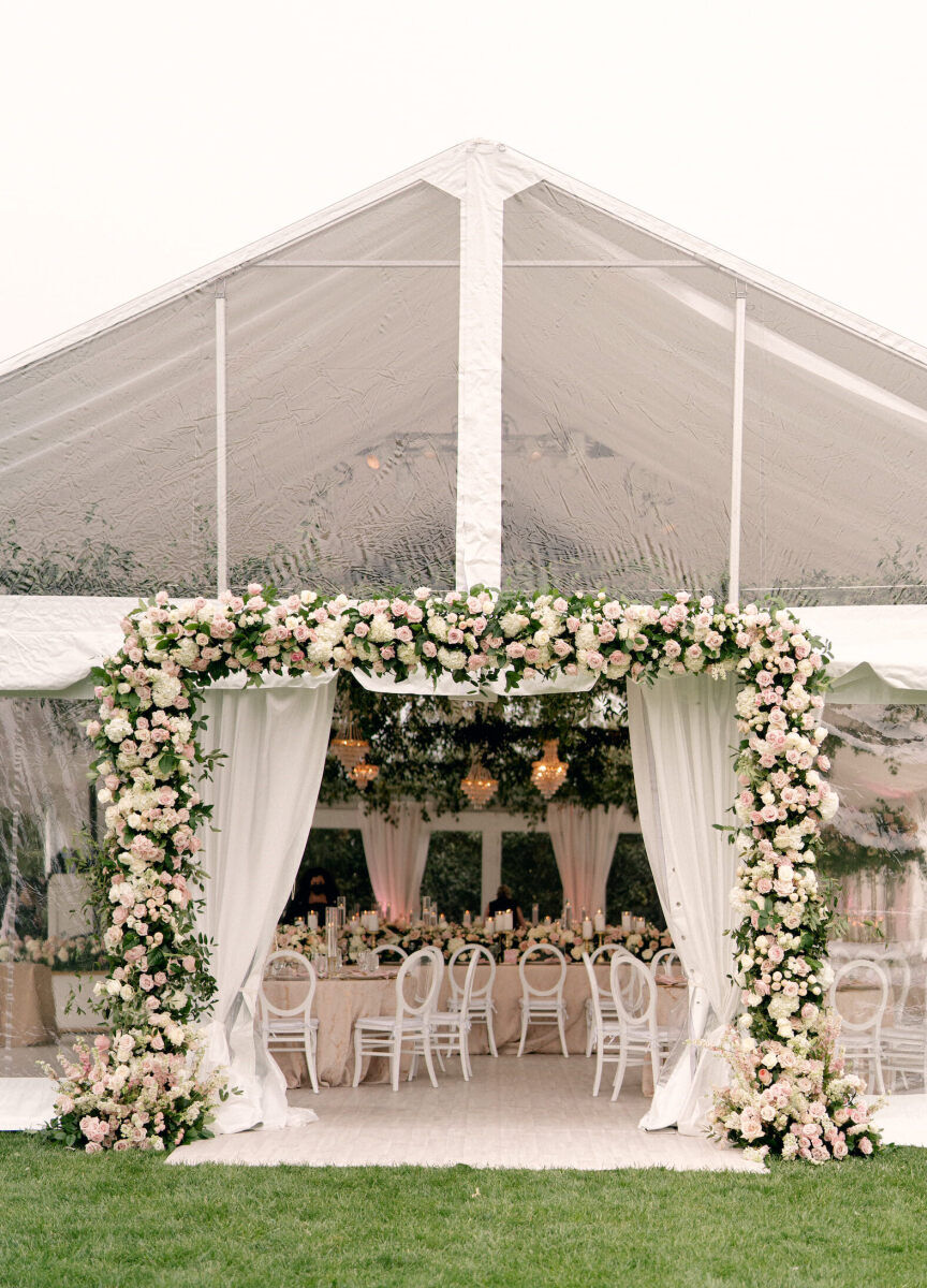 Tented Wedding: The entrance to a tented wedding reception, with a high-impact floral installation of white and pink blooms and fresh greenery.