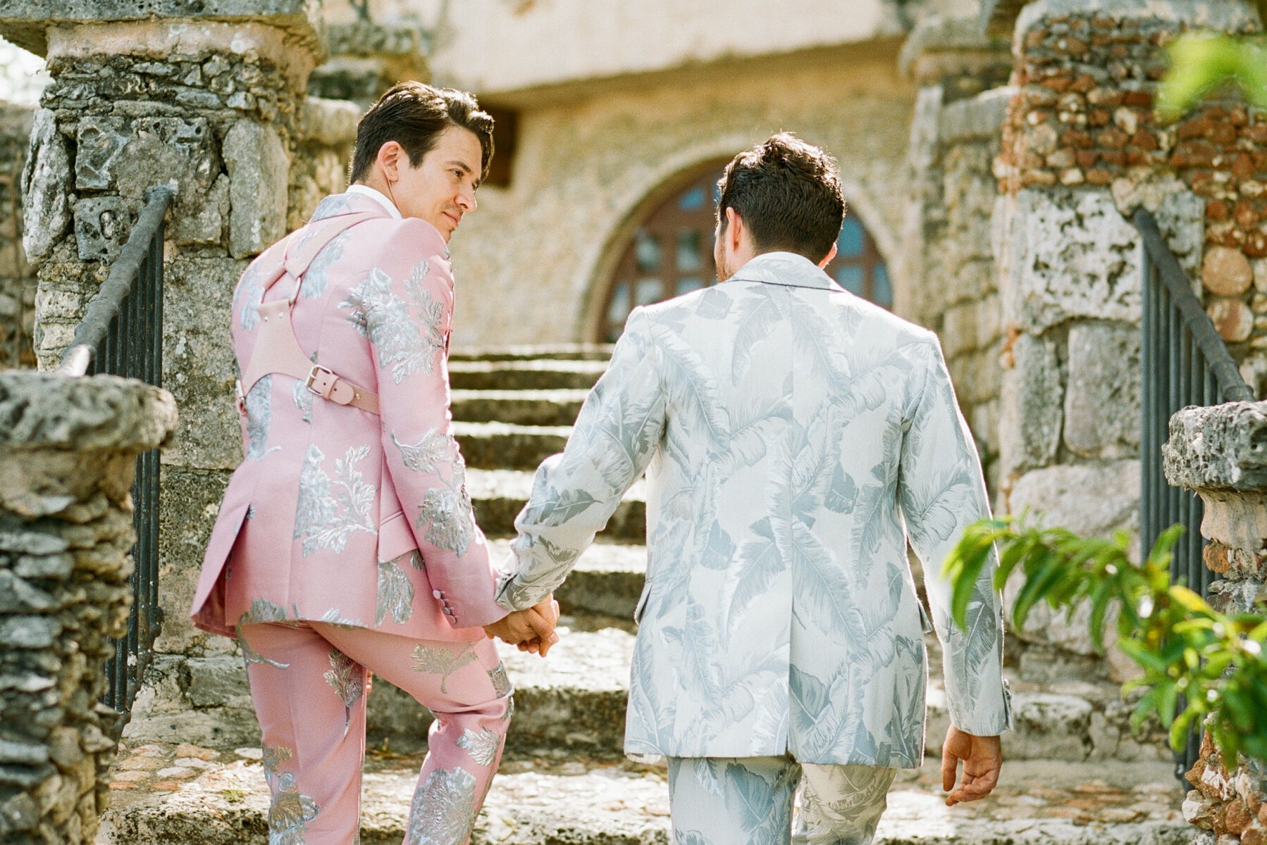 Tropical Wedding: Two grooms walking up the stairs at their wedding venue.