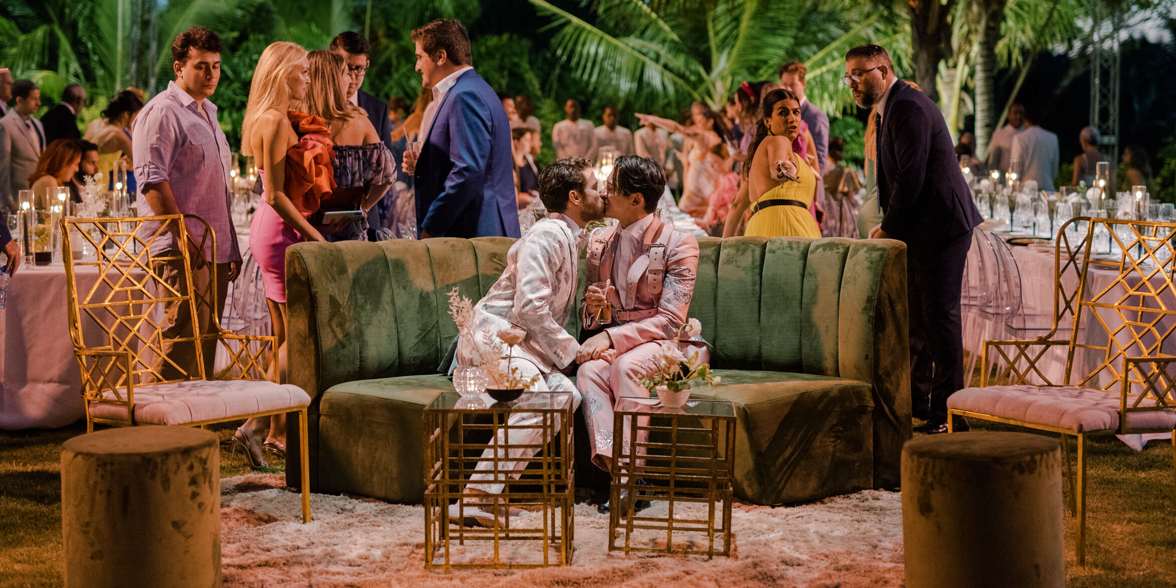 Tropical Wedding: Two grooms sharing a kiss during their wedding reception.
