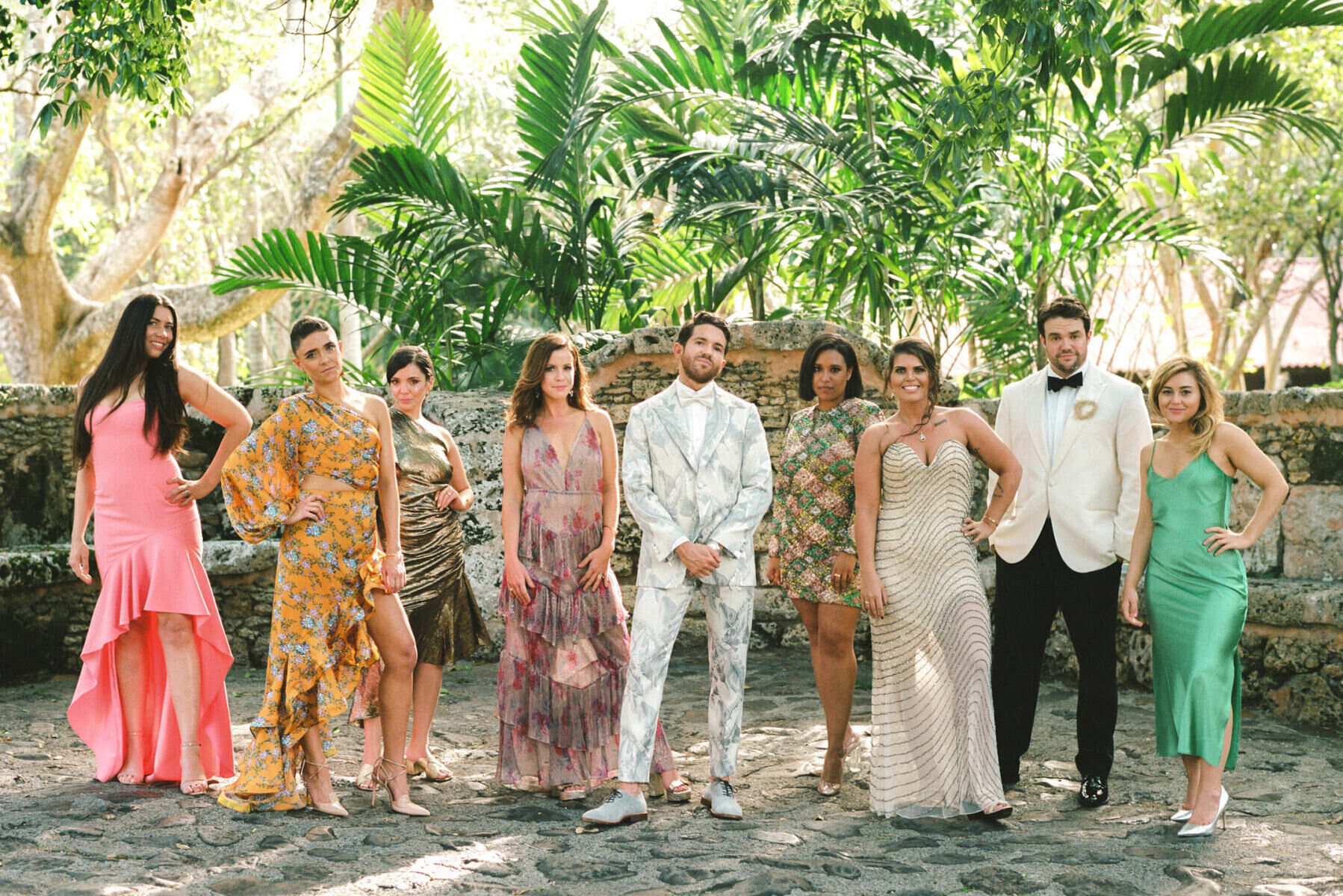 Tropical Wedding: Wedding party posing infant of Dominican Republic wedding venue in mismatched floral attire.