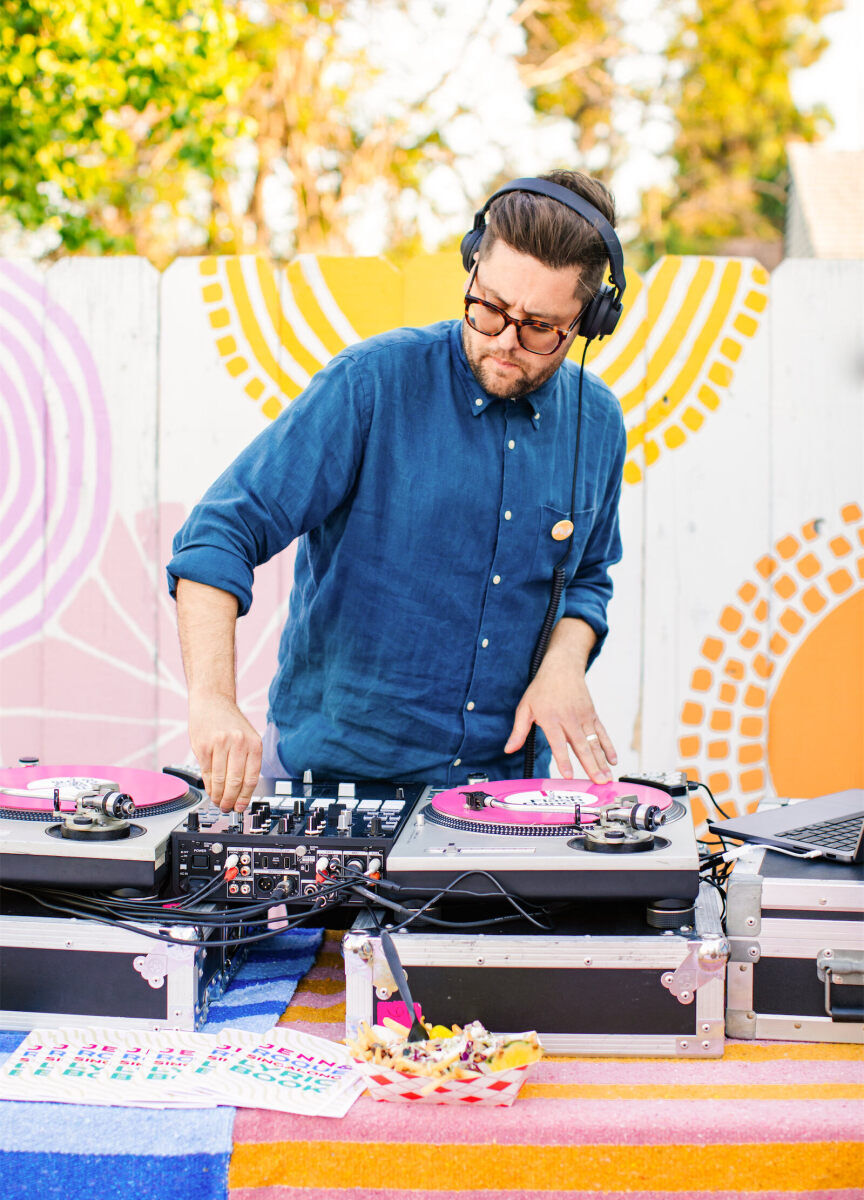A DJ spins records during a vibrant outdoor wedding reception in California.