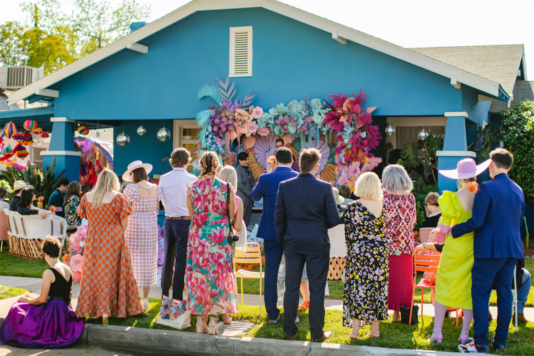 Guests enjoy a vibrant outdoor wedding at a couple's teal green home in Fresno.