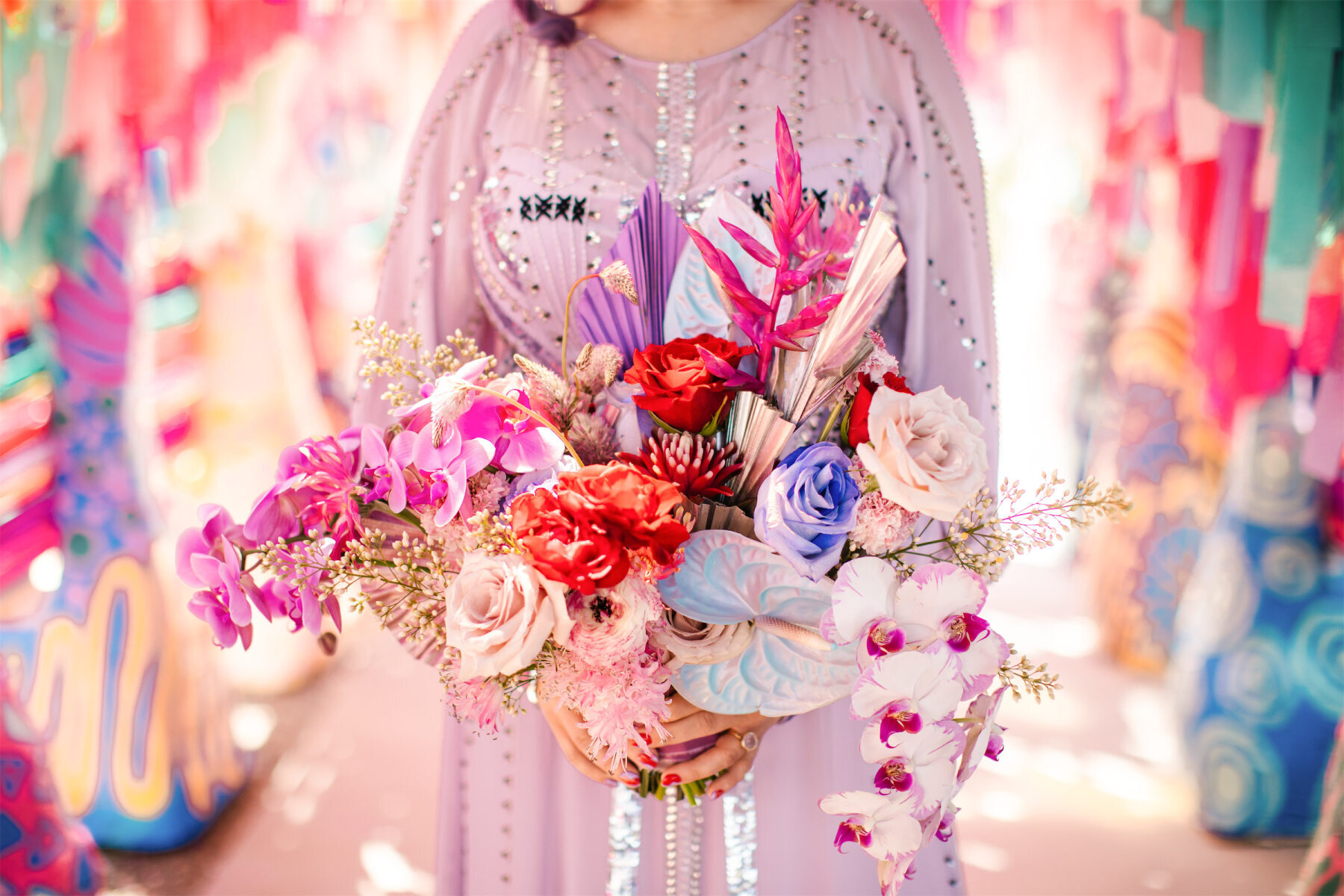 A bride wearing a light purple dress holds her multi-color bouquet with iridescent elements and a textural combination of flowers at her vibrant outdoor wedding in Fresno, California.