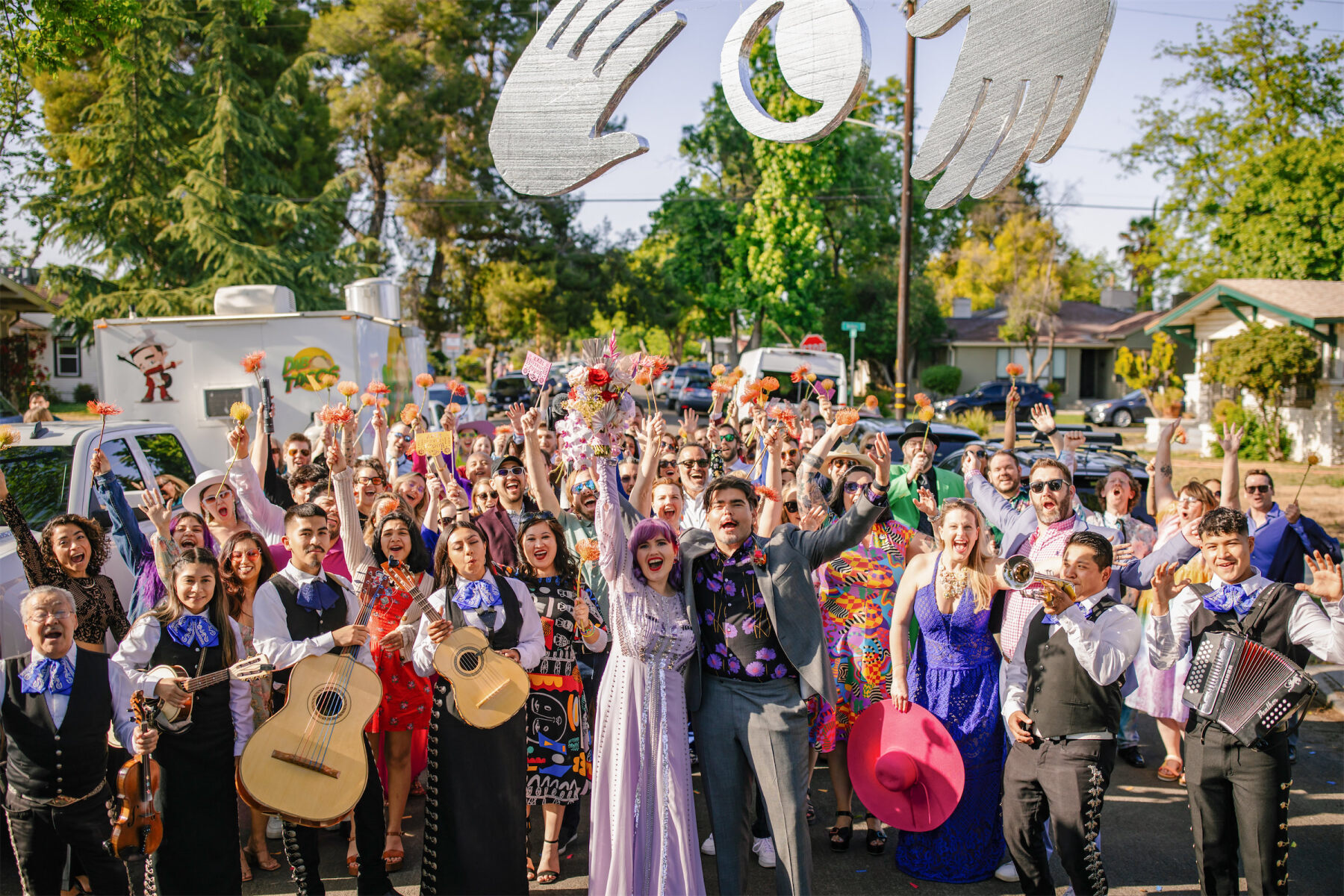 A group photo, including the mariachi band that led guests on a post-ceremony parade at a vibrant, outdoor wedding, was snapped when everyone got back to the wedding venue.
