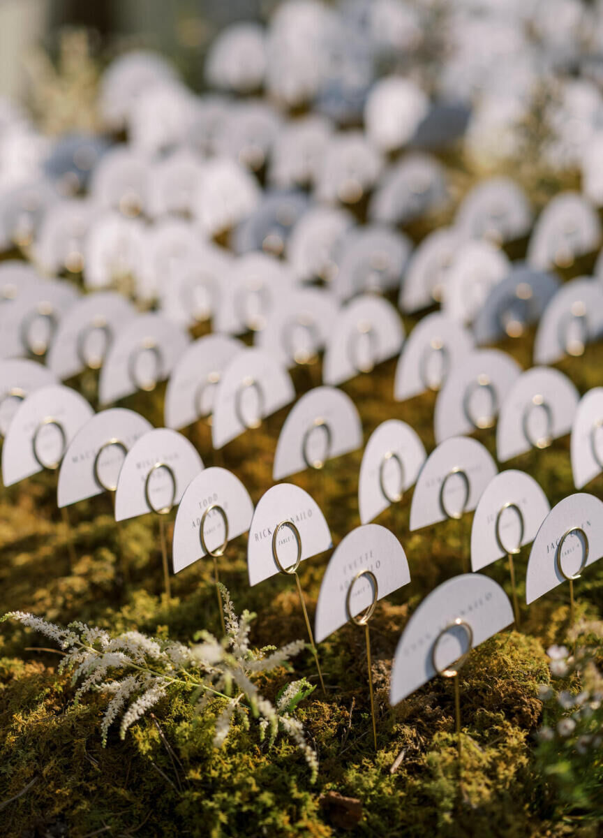 Half-moon shaped escort cards displayed in a bed of moss guided guests to their seats at a waterfront wedding.