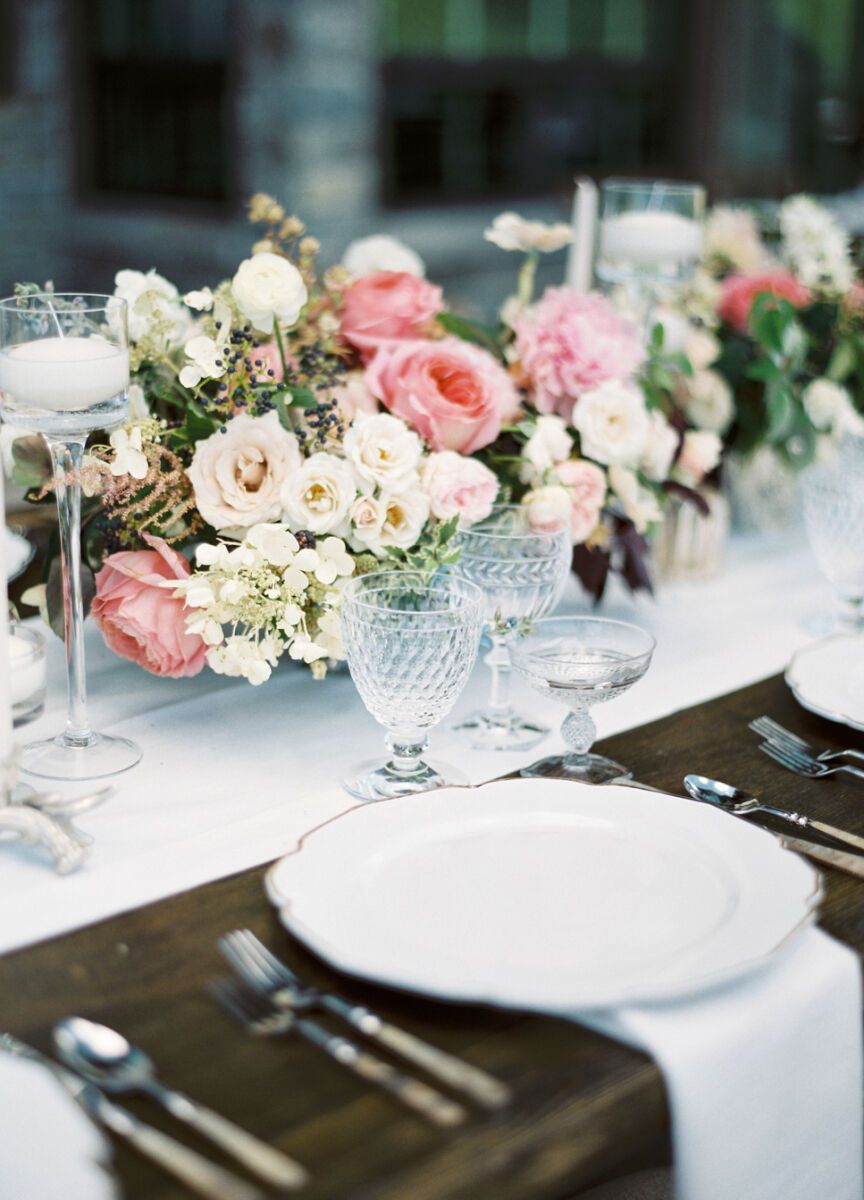 Wedding budget: Wedding reception place setting, featuring white china and linens with pink and white floral centerpieces 
