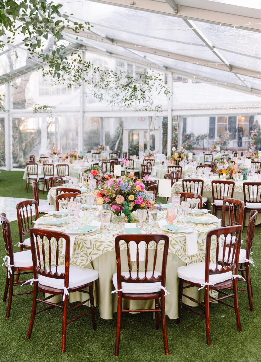 A spring-hued tented wedding reception with a mix of round and square tables.