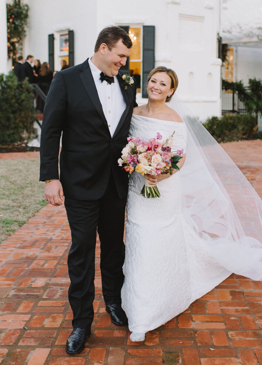 Wedding couple walking arm and arm down a brick path.