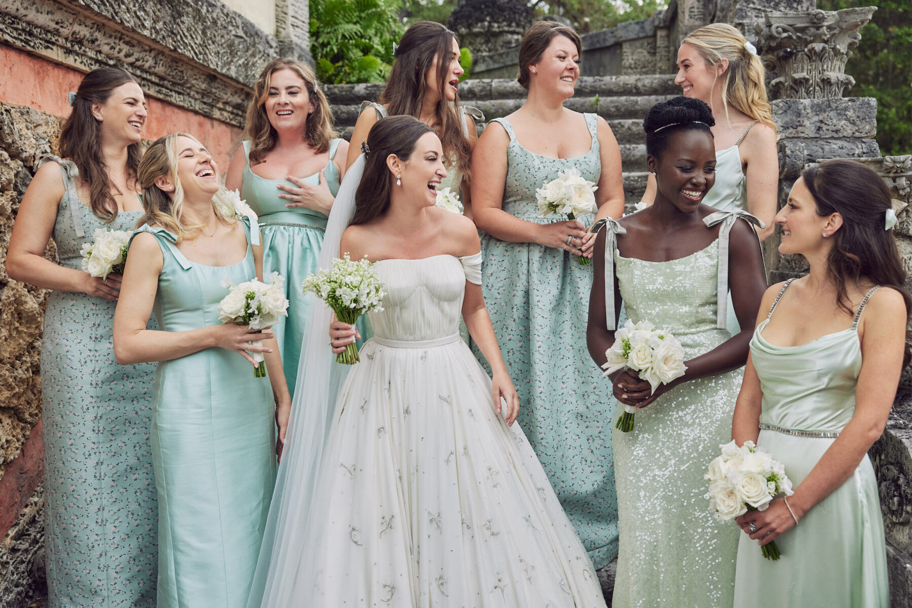 Wedding Dress Shopping: A bride laughing with her bridesmaids, who are all dressed in shades of green.