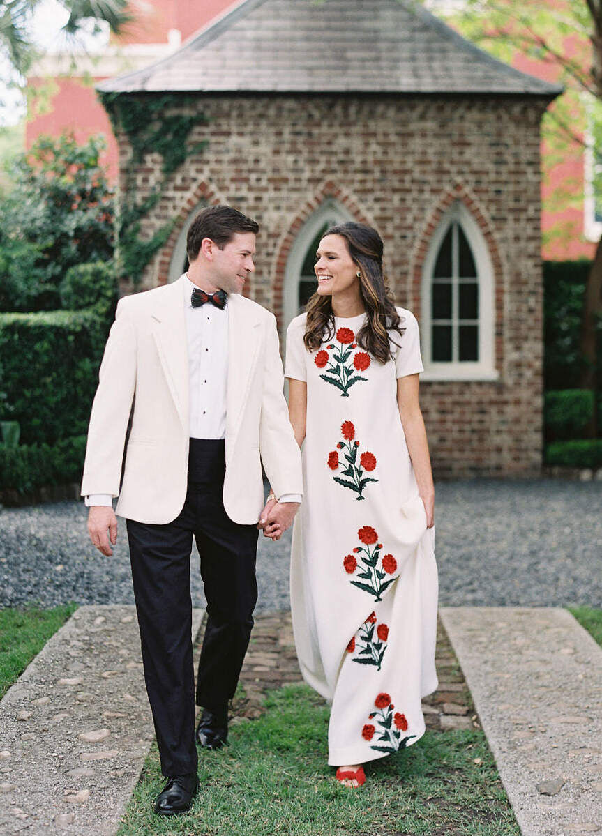 Wedding Dress Shopping: A bride smiling at her groom, wearing a short-sleeve dress with red floral designs on it.
