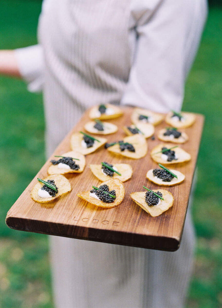 Wedding Etiquette Budget: A server holding up a tray of chips topped with caviar.