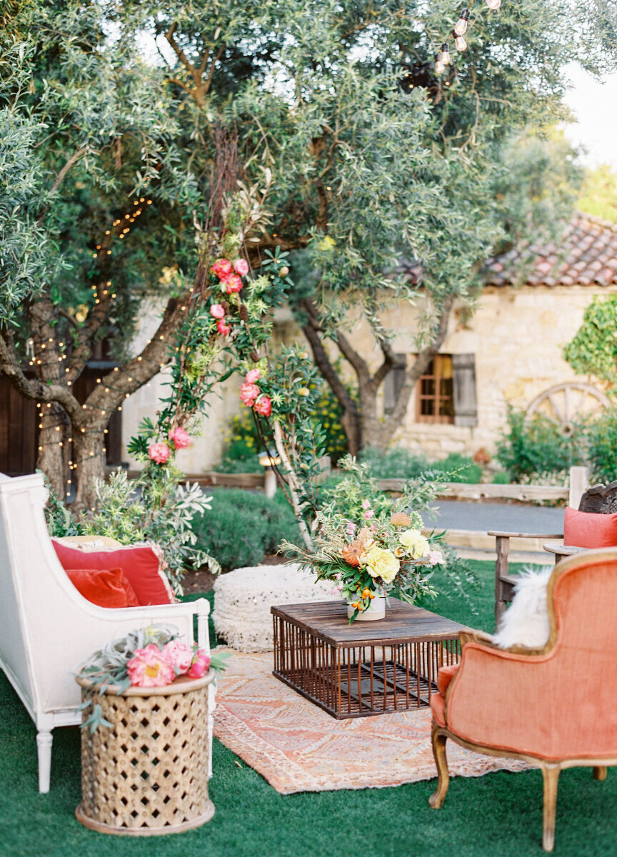 Wedding Etiquette: An outdoor seating area with pink accents near a tree and Spanish-style building in the background.