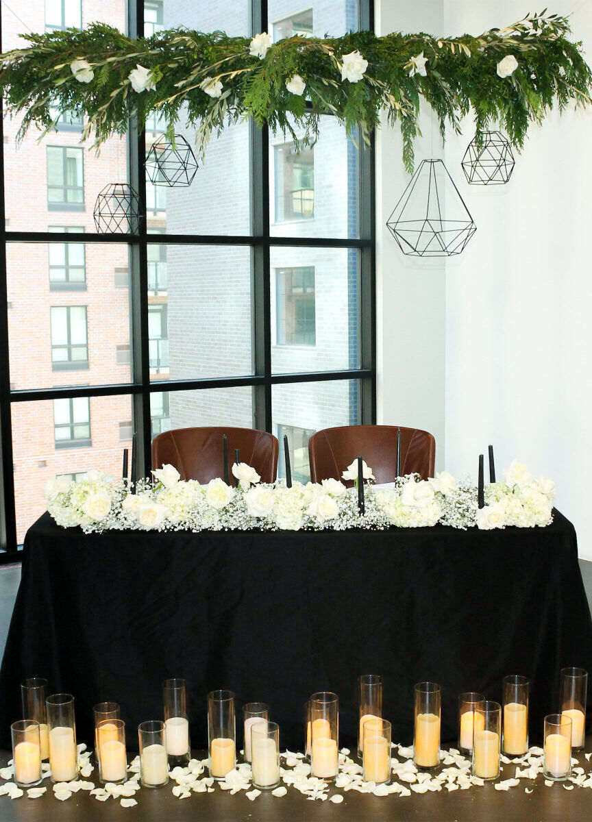 Wedding News: A sweetheart-style reception table in front of a large loft-style window at Mosaic Event Venue.