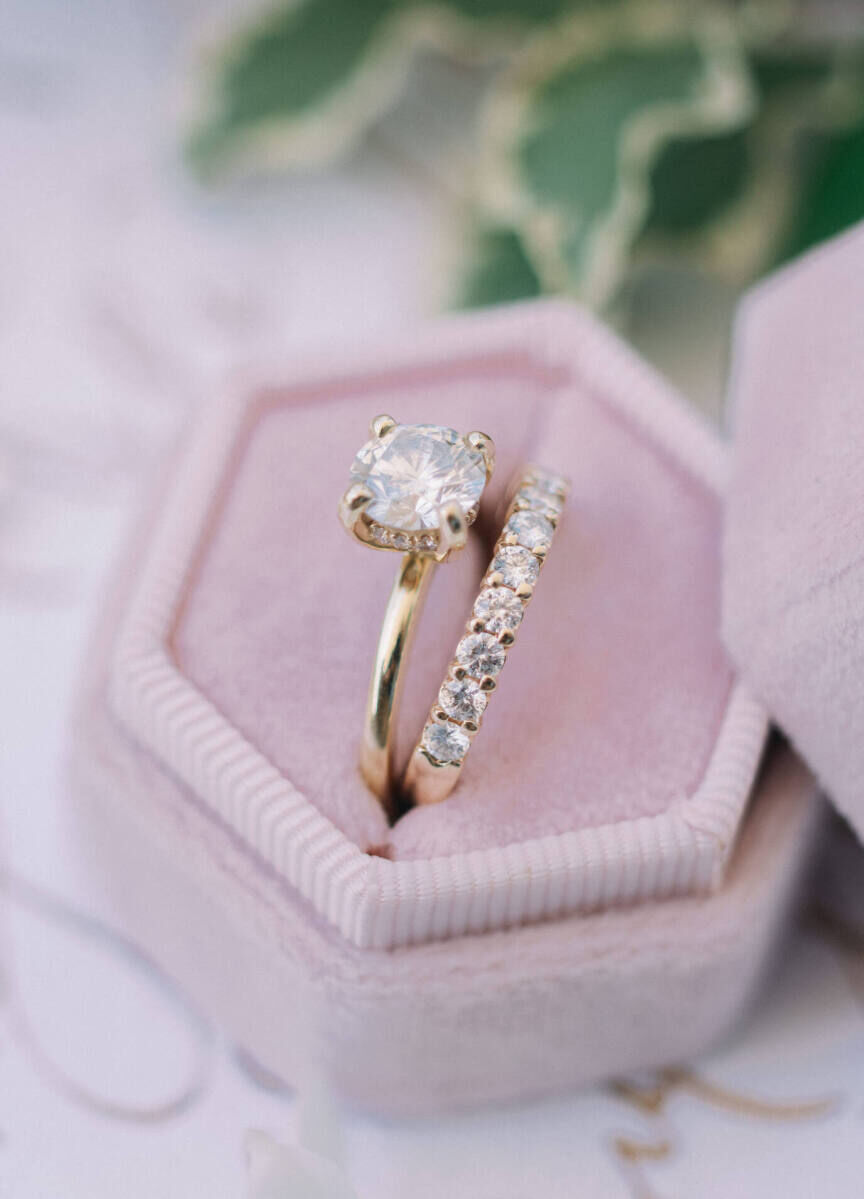 Wedding Ring Design: A round cut engagement ring in a prong setting next to an eternity wedding band in a hexagonal pink ring box.