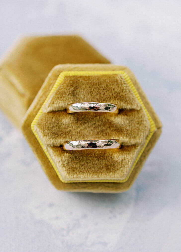 Wedding Ring Design: Two metal wedding bands in a burnt-yellow color suede ring box.