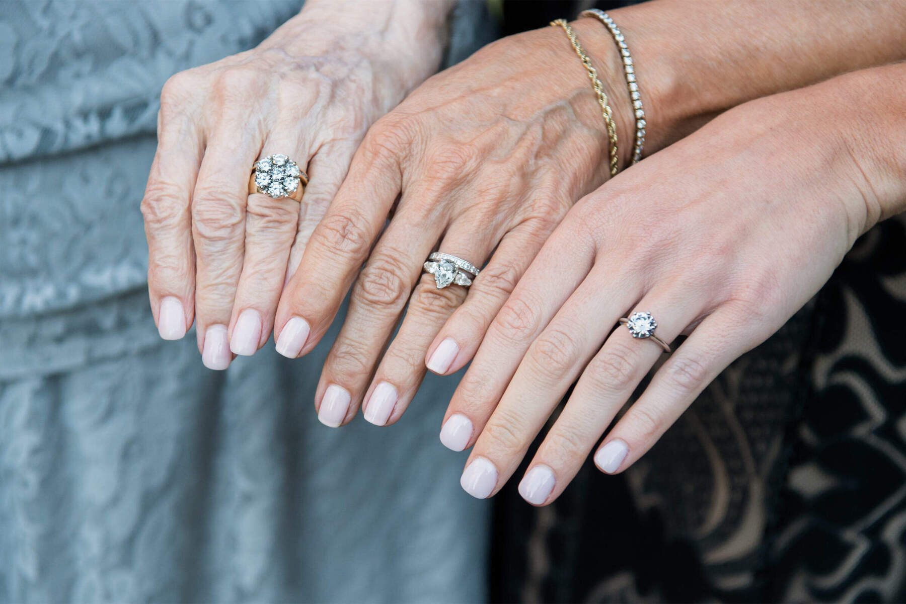 Wedding Ring Design: Three generations of hands with engagement rings on their ring fingers.