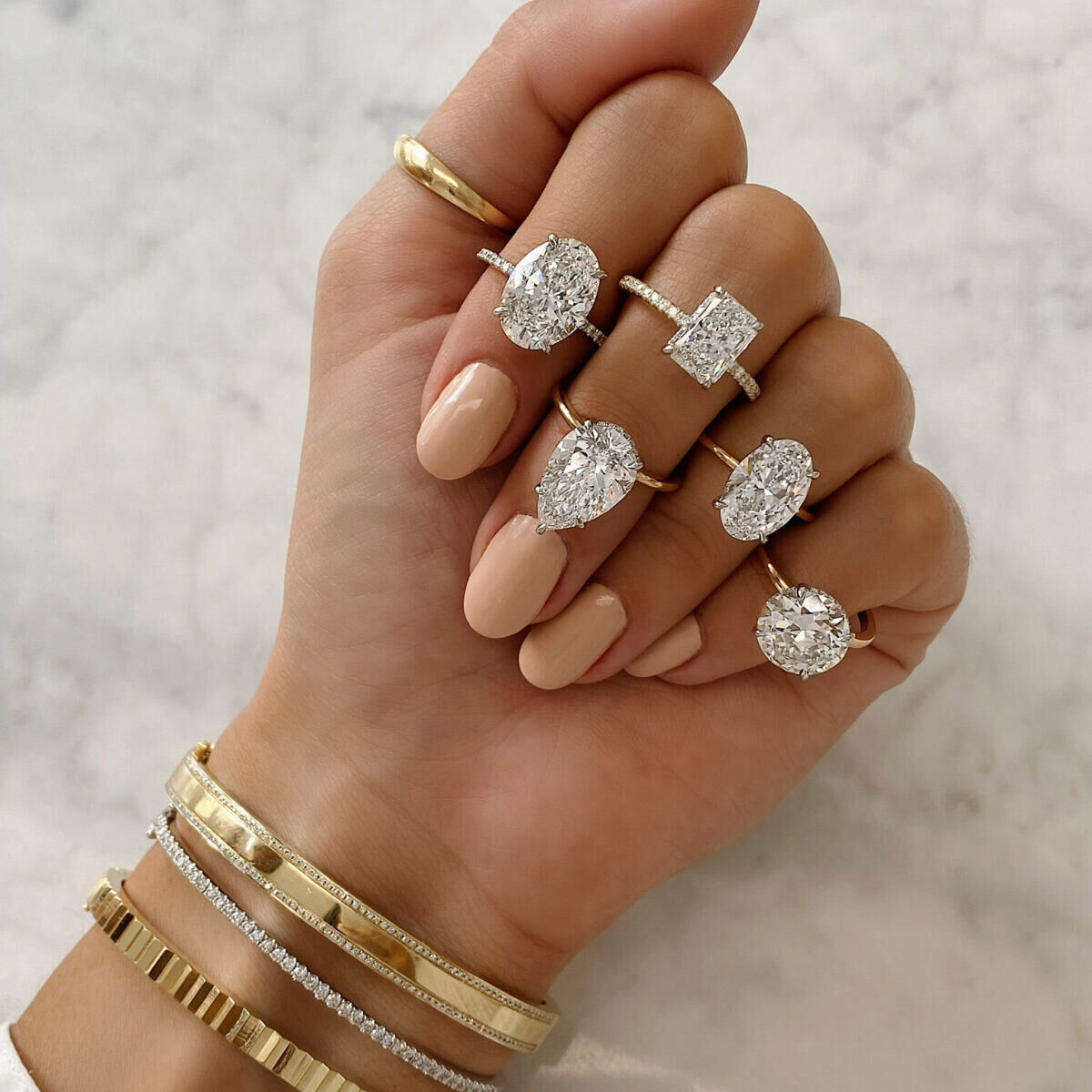 Wedding Ring Design: Five different engagement rings being worn on one hand for display.